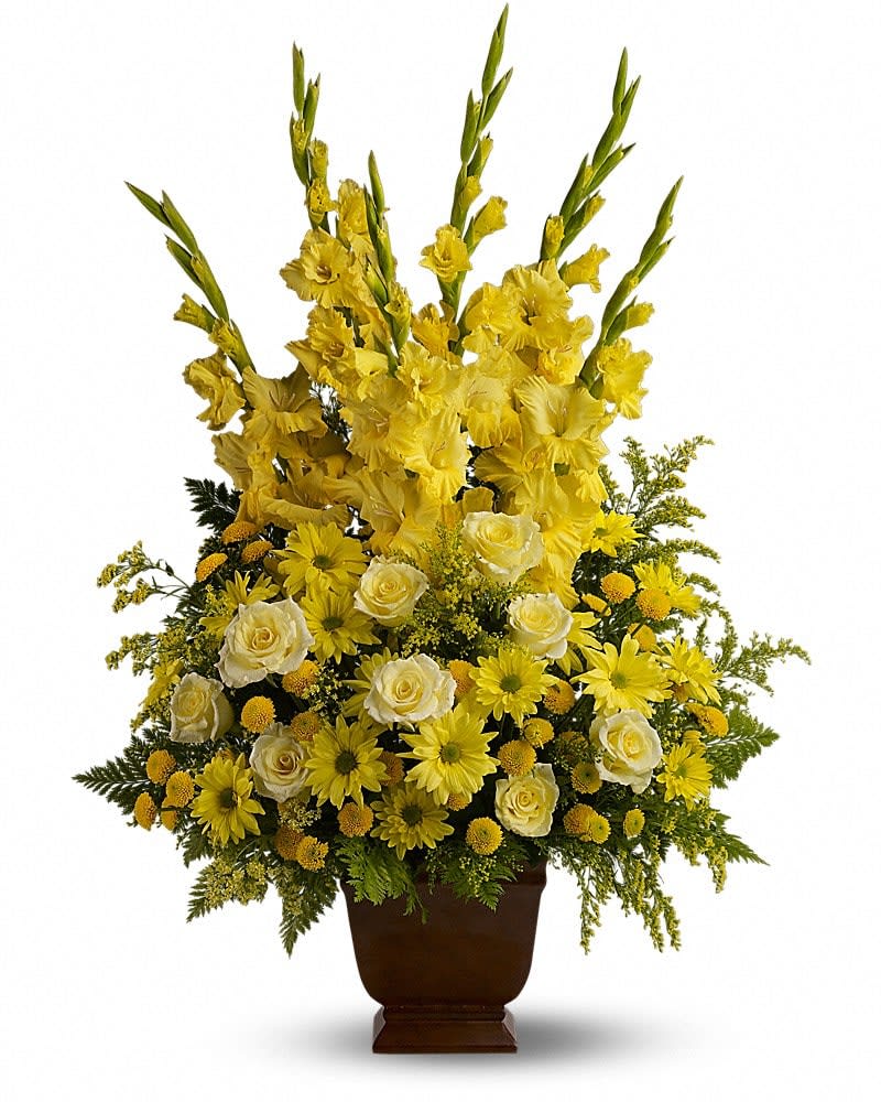 Tall yellow and white arrangement with gladiolus, roses, and daisies in a dark pedestal vase