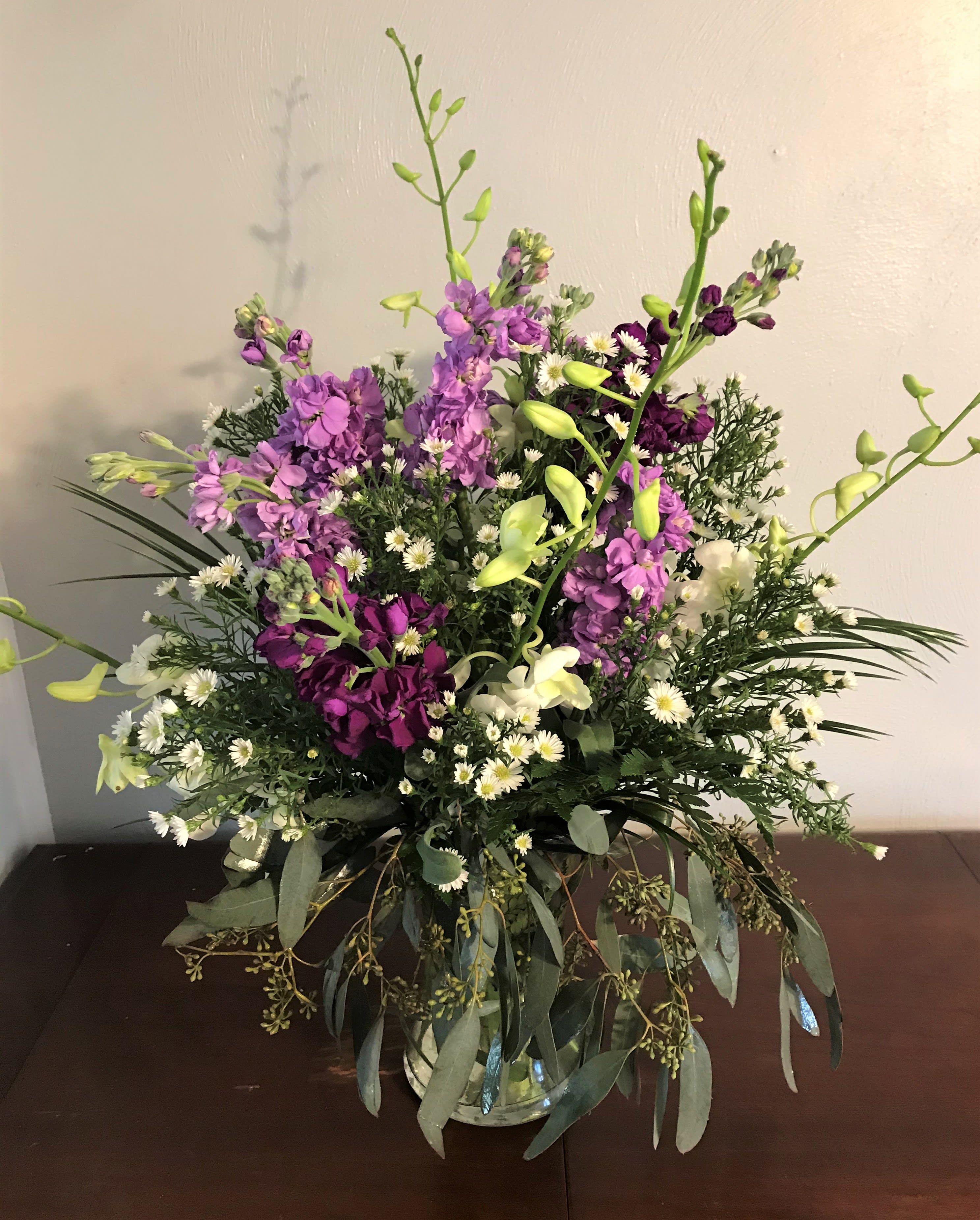 Purple and white mixed flower arrangement in a glass vase