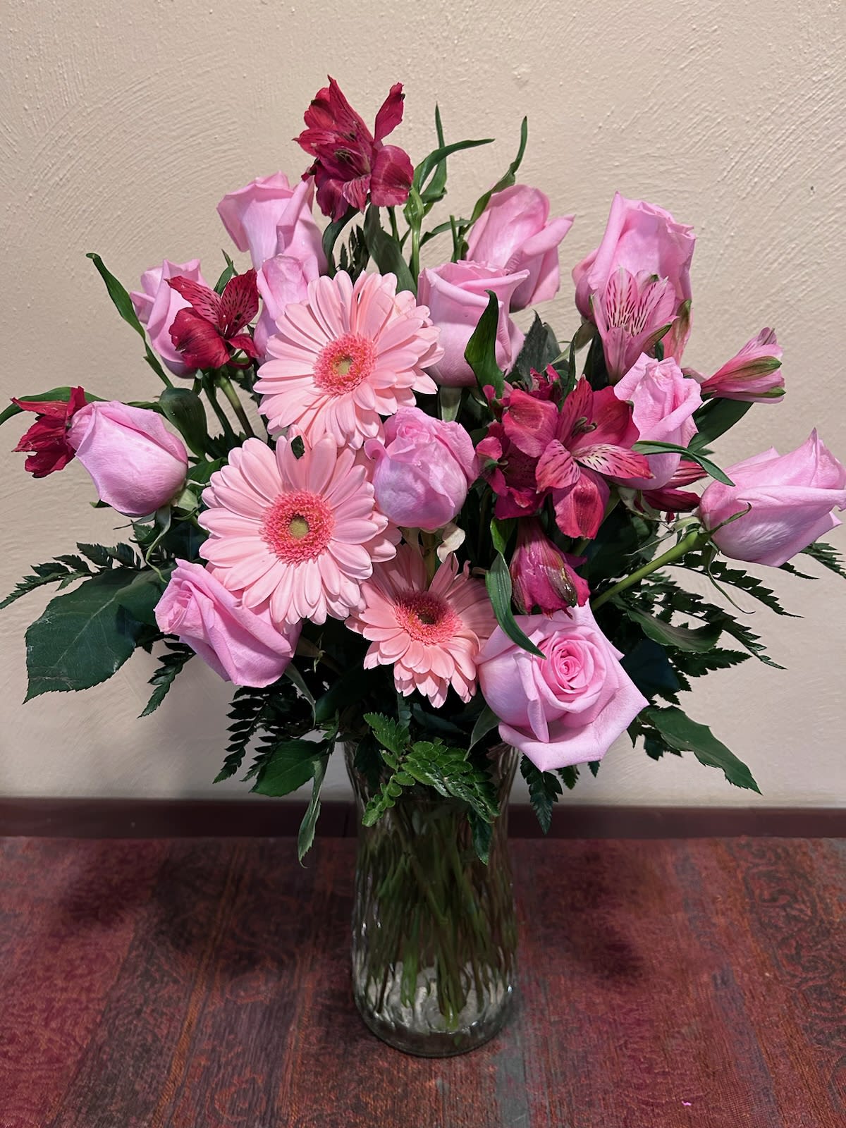 Pink roses, gerbera daisies, and alstroemeria in a glass vase