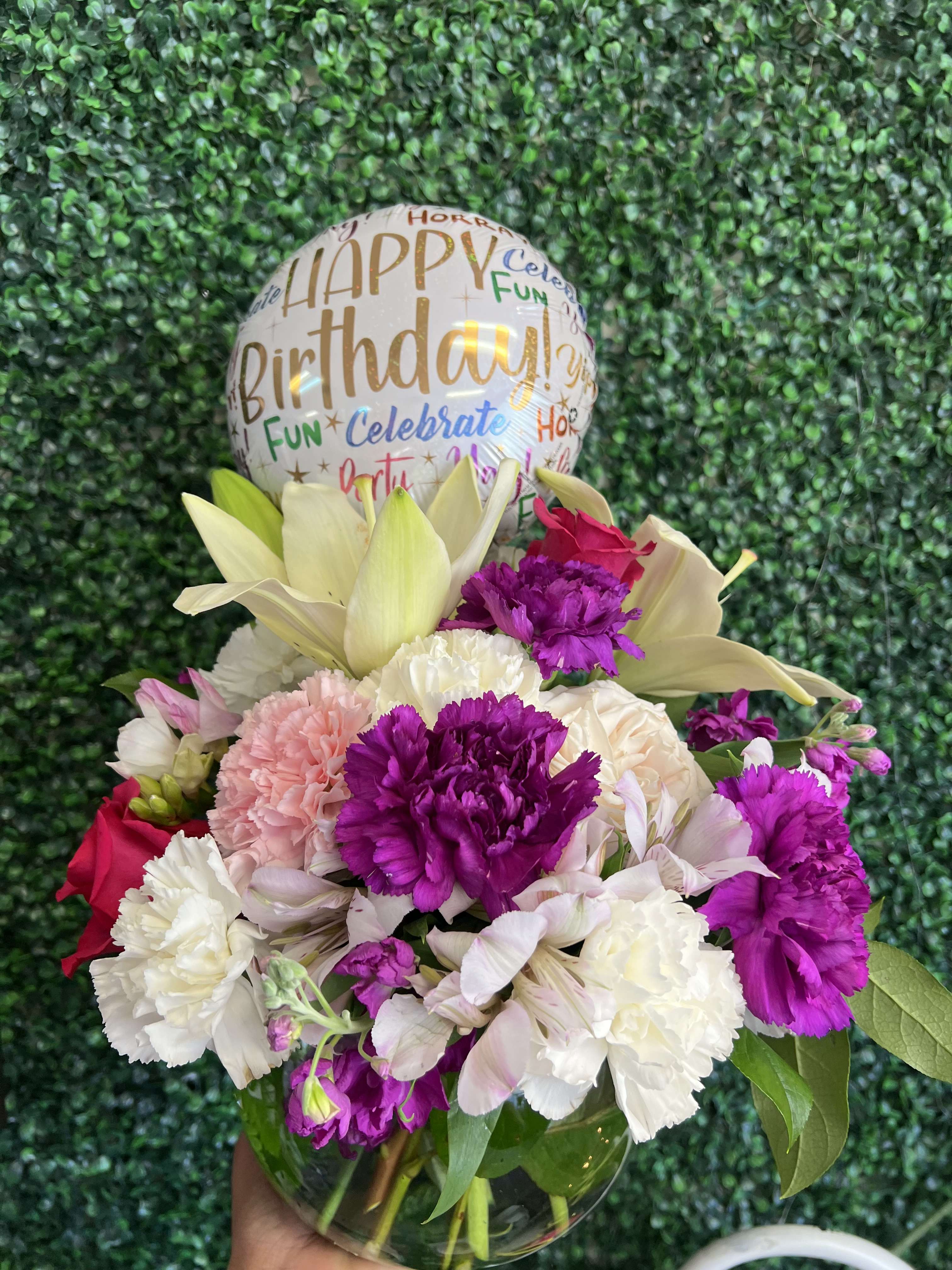 Birthday balloon above a mixed bouquet in a glass vase