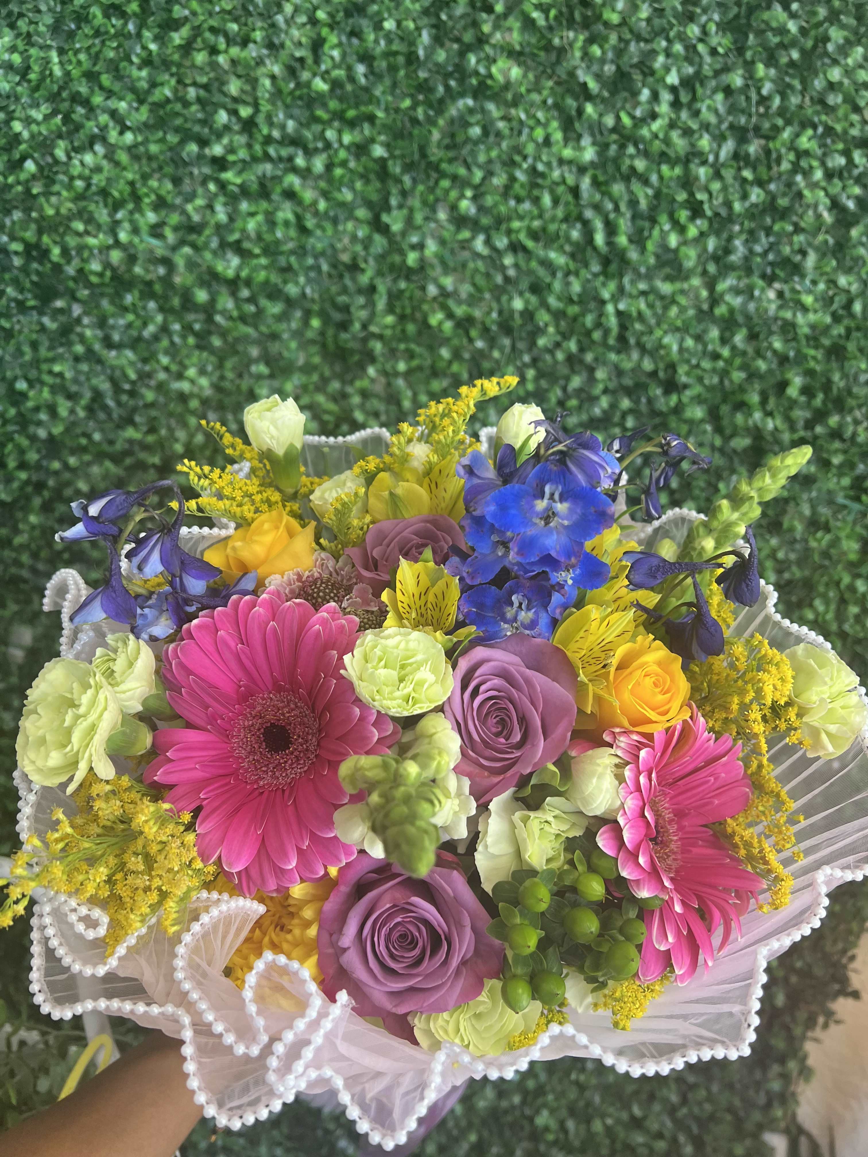 Colorful bouquet with pink gerberas, purple roses, and blue flowers