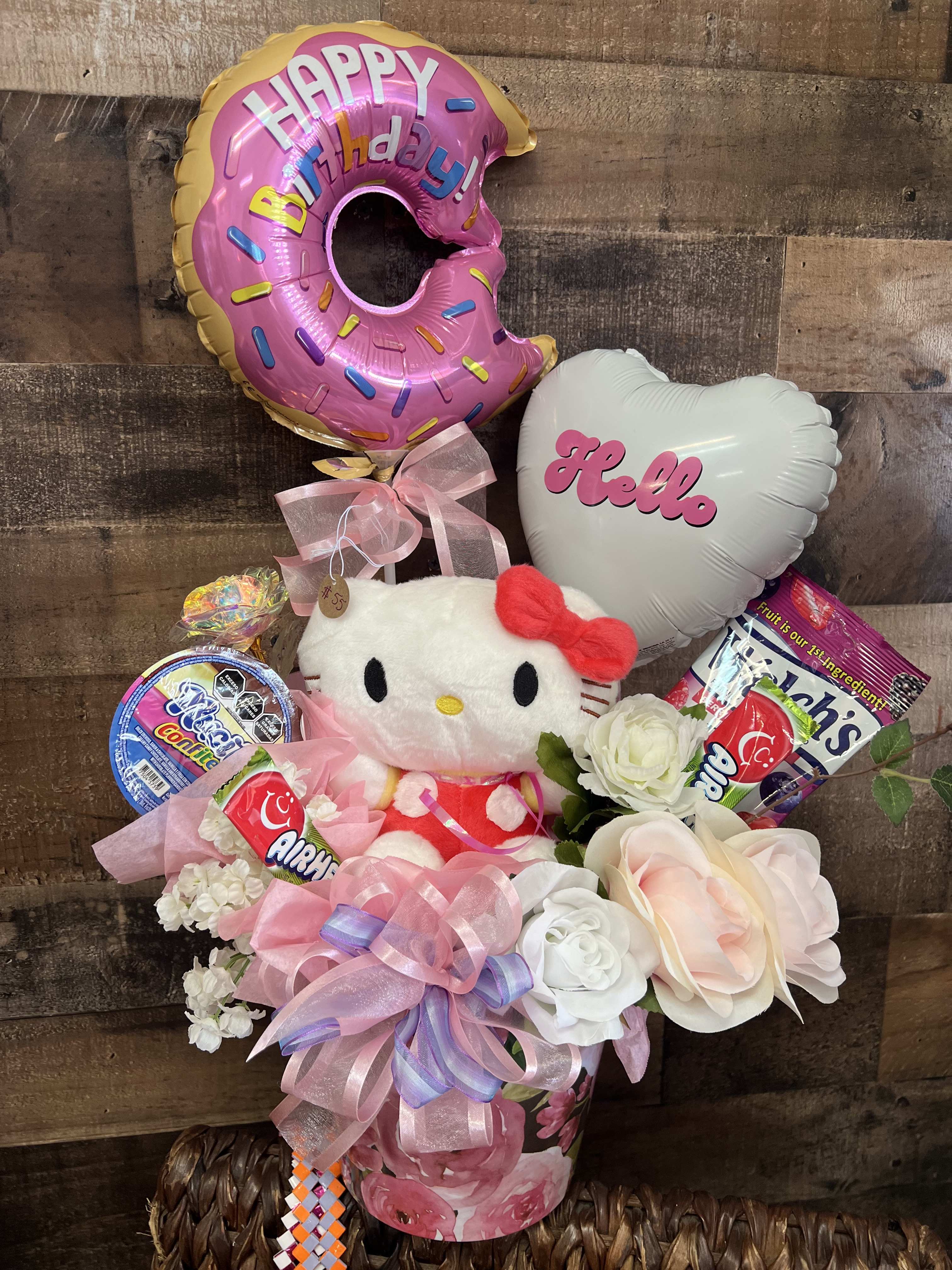 Hello Kitty birthday gift arrangement with balloons, candy, and flowers