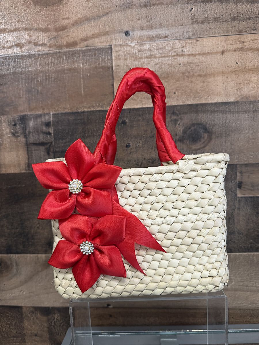 Artisan Purse - Red Theme - A handcrafted woven straw handbag trimmed with satin ribbon flowers and sparkling rhinestone centers makes a charming gift-ready accessory for a spring baby shower, birthday, or hostess present. This small woven basket-style arrangement reads like a polished keepsake rather than a traditional bouquet-its bright blue and pale blue satin blooms (with jeweled centers) or the softer ivory, champagne and gold ribbon flowers bring instant cheer and a touch of couture to the recipient's moment.  Each handbag features natural straw texture, two wrapped handles, and decorative satin ribbon flowers finished with rhinestone brooch centers for a playful yet elegant look. Sizes are compact and structured-perfect for pairing with small gifts, note cards, or a single posy if the recipient prefers-even when no fresh flowers are included the piece feels celebratory. Choose the colorway that suits the occasion: bold red flowers for a festive pop, bright blue for a spring or baby-themed surprise, or neutral champagne and ivory for a more formal gift.