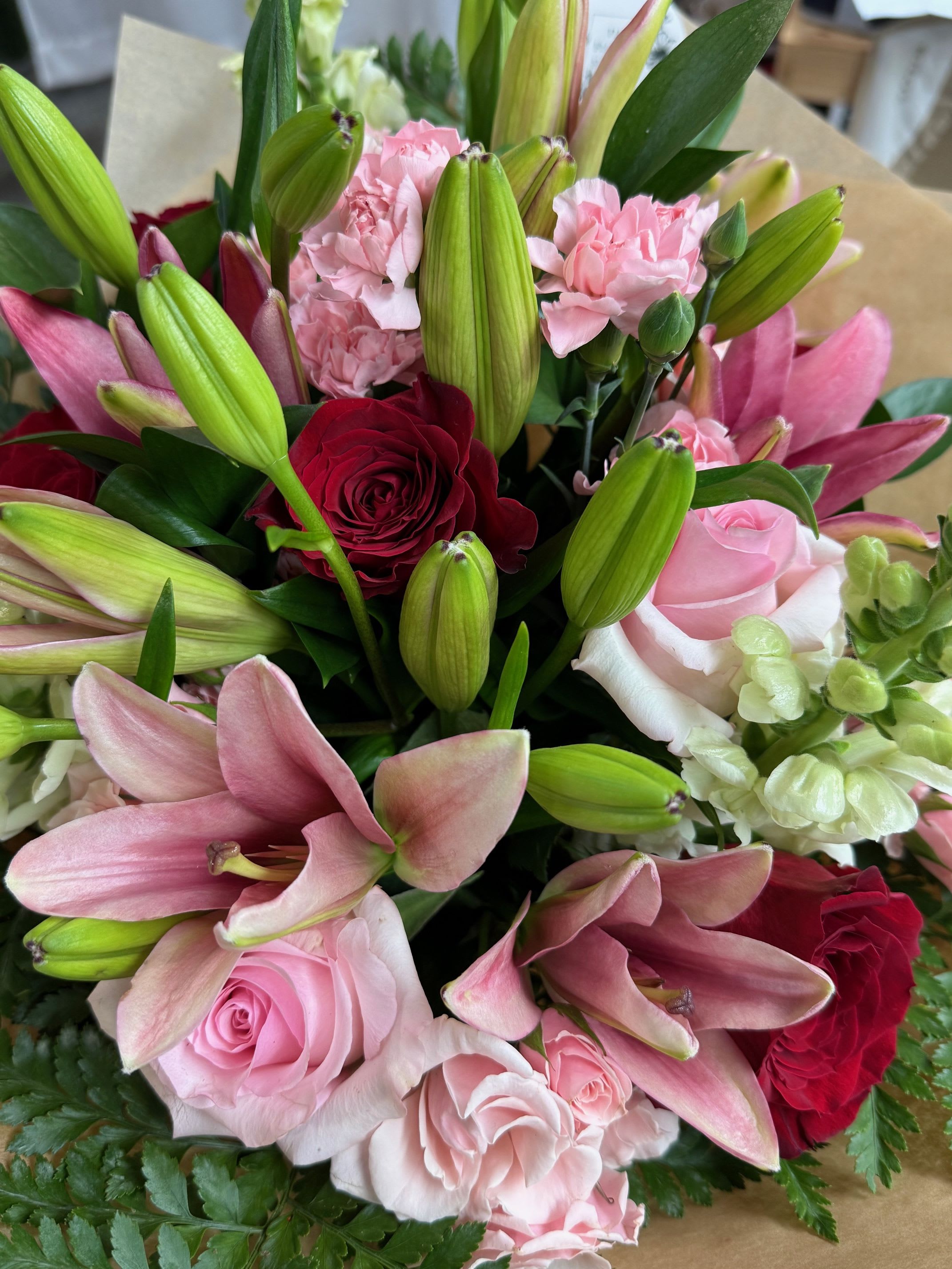 Bouquet of pink lilies, roses, and carnations with a red rose accent
