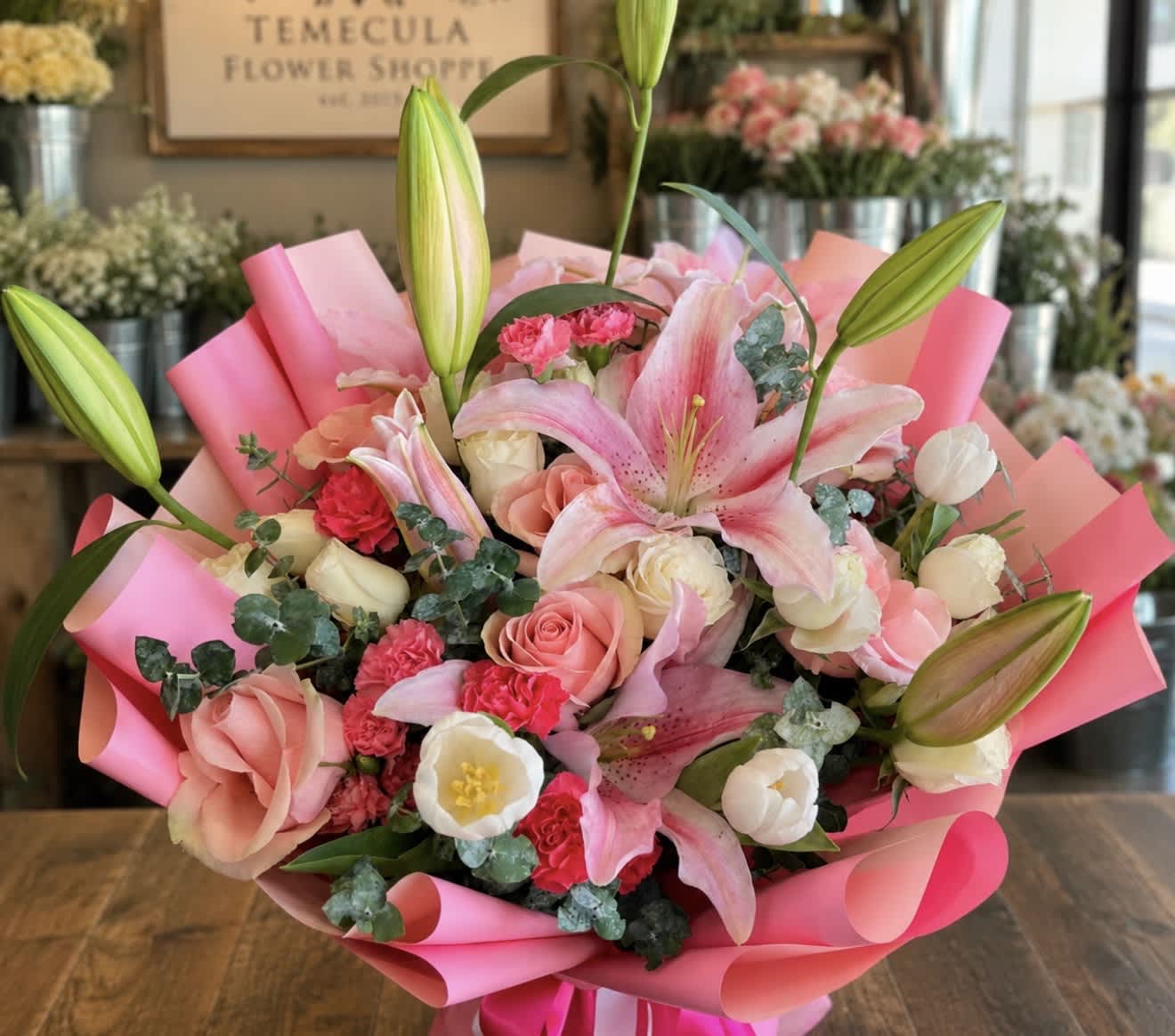 Pink lily and rose bouquet wrapped in bright pink paper