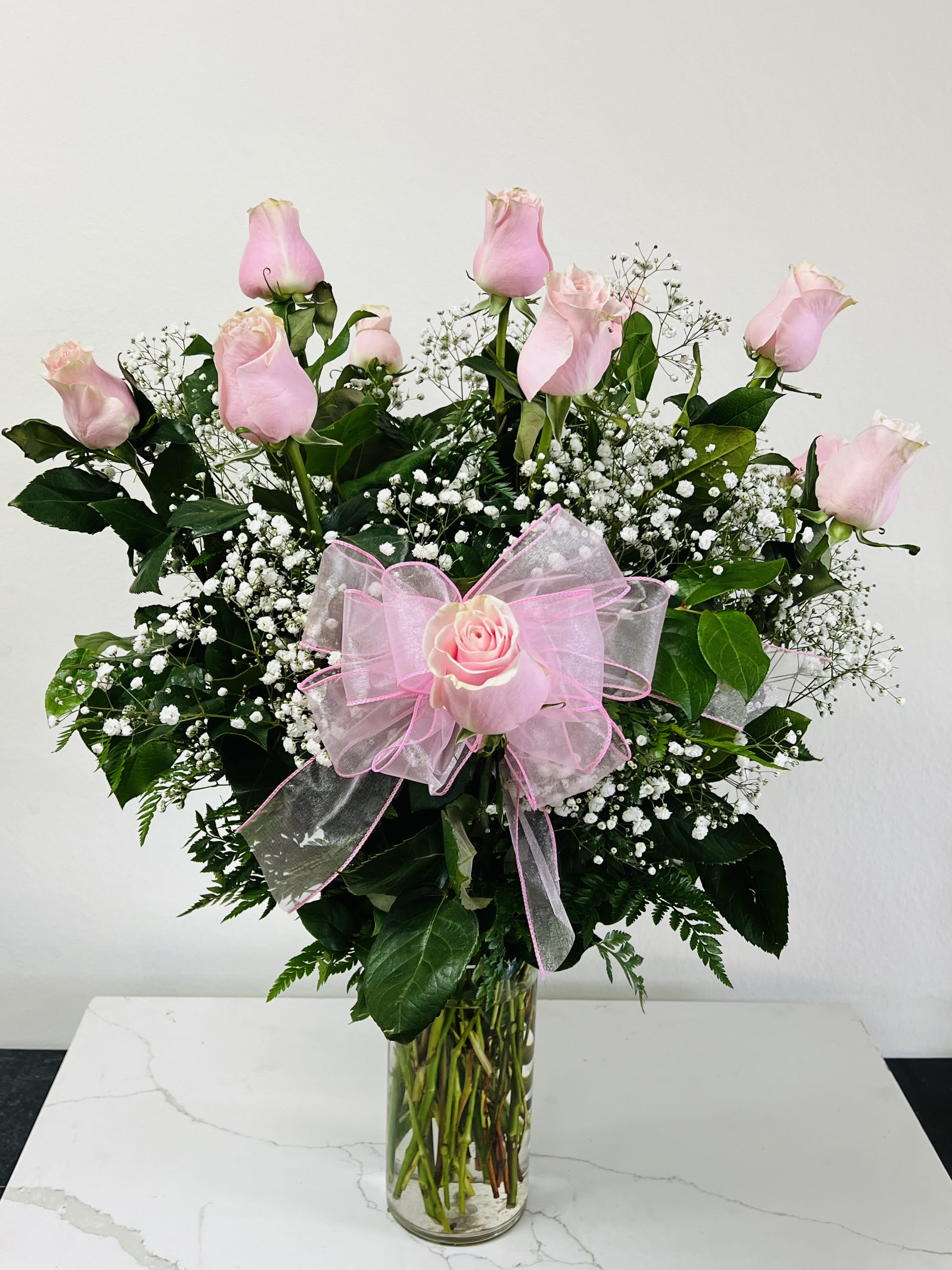 Pink roses in a clear glass vase with a pink bow