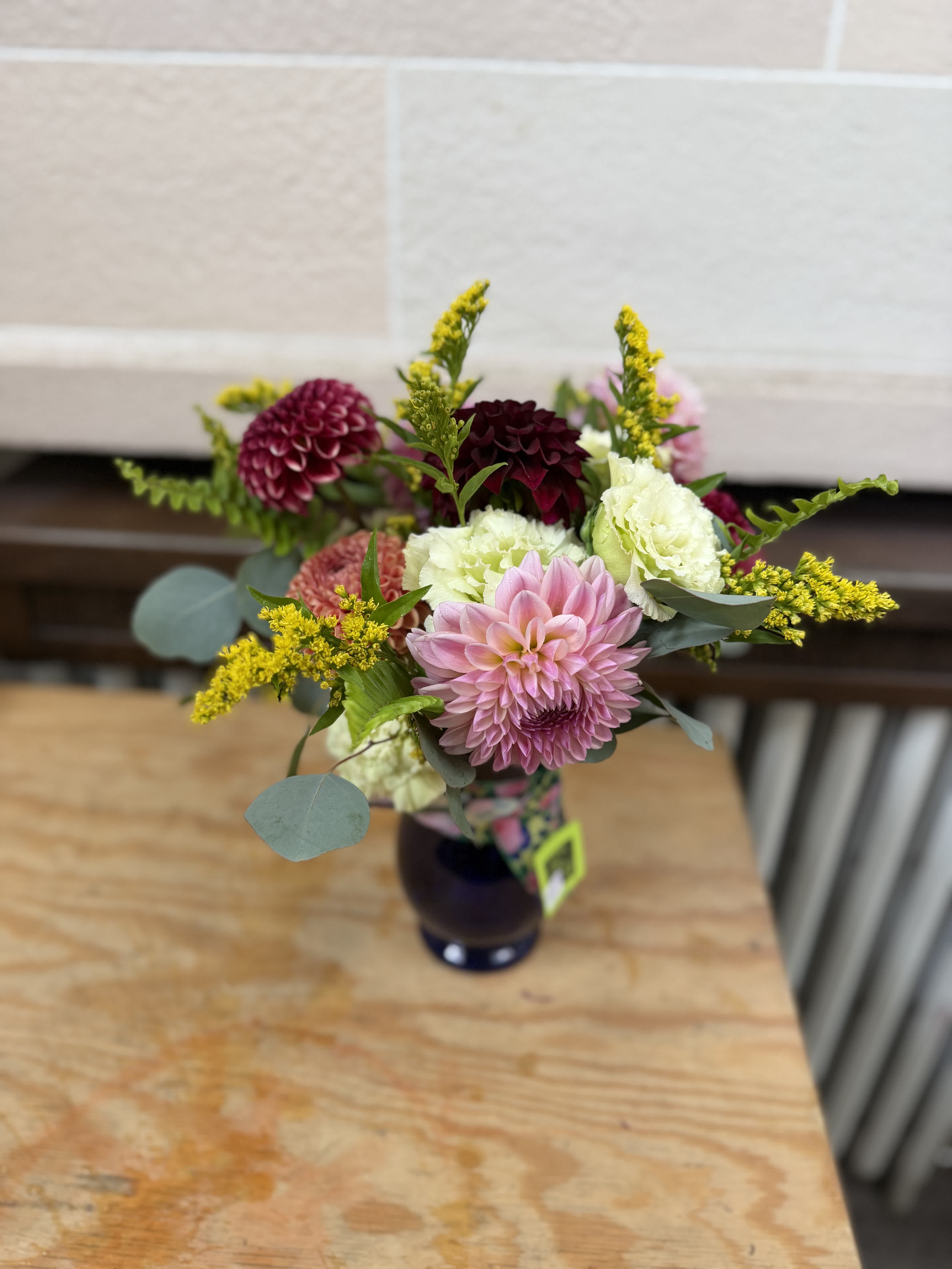 Mixed bouquet with pink, white, and burgundy blooms in a dark vase