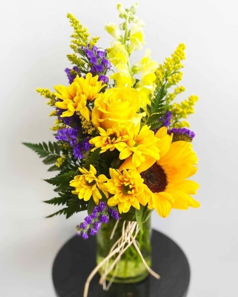 Yellow and purple mixed flower arrangement in a glass vase