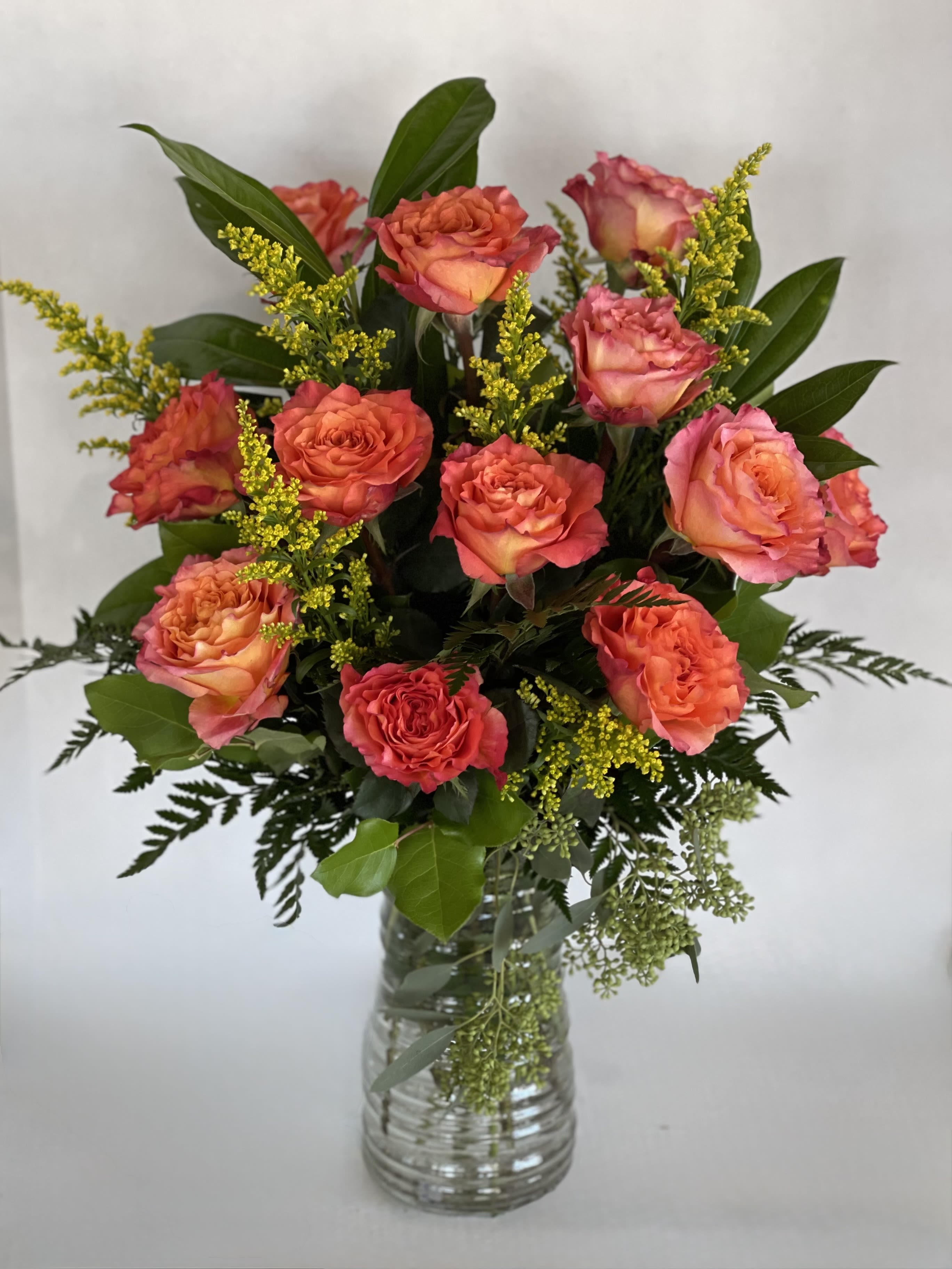 Coral and pink roses arranged in a clear glass vase