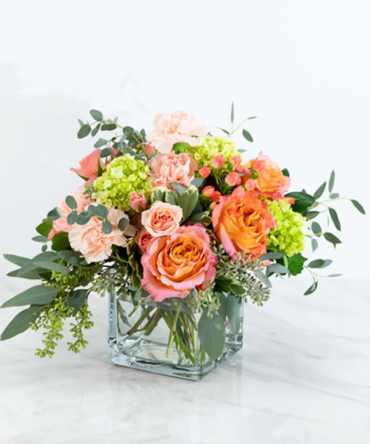 Mixed bouquet of pink and orange roses in a clear glass vase