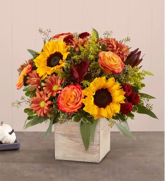 Mixed bouquet with sunflowers, roses, and mums in a wooden cube vase