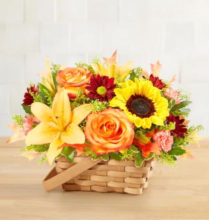 Basket arrangement with sunflowers, roses, lilies, and red daisies