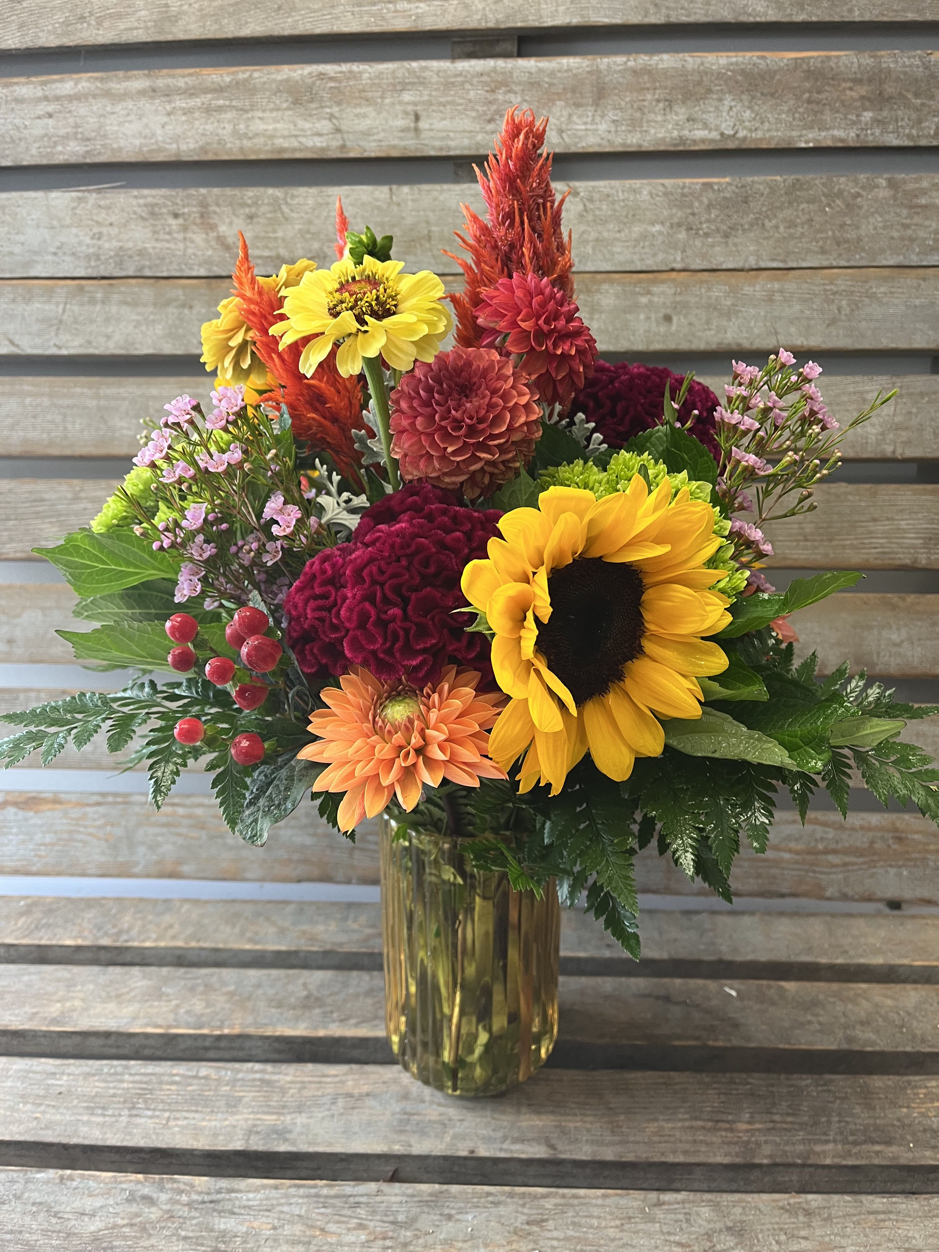 Colorful mixed bouquet in a glass vase with sunflowers and dahlias
