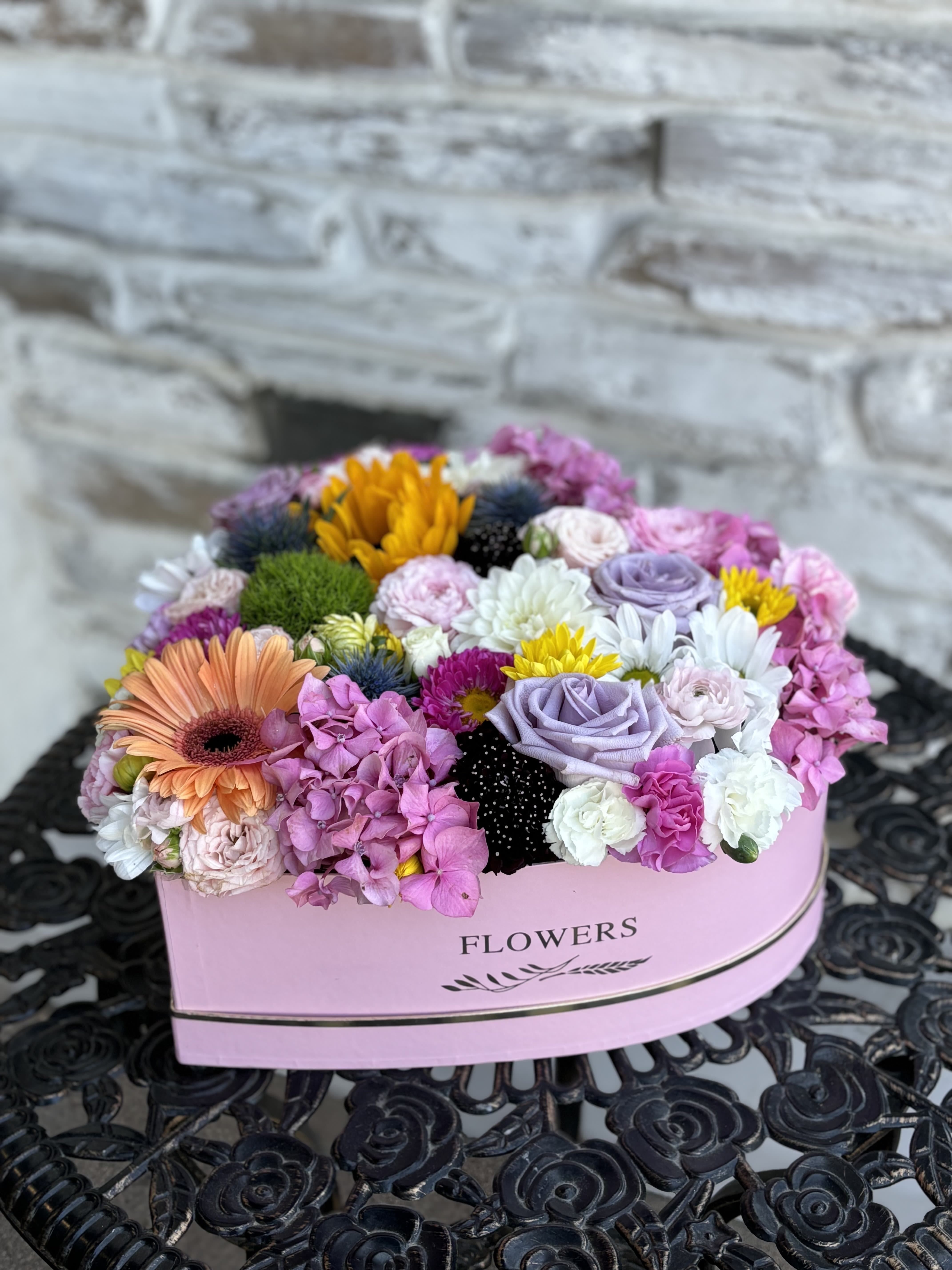 Mixed pastel flower arrangement in a pink heart-shaped box