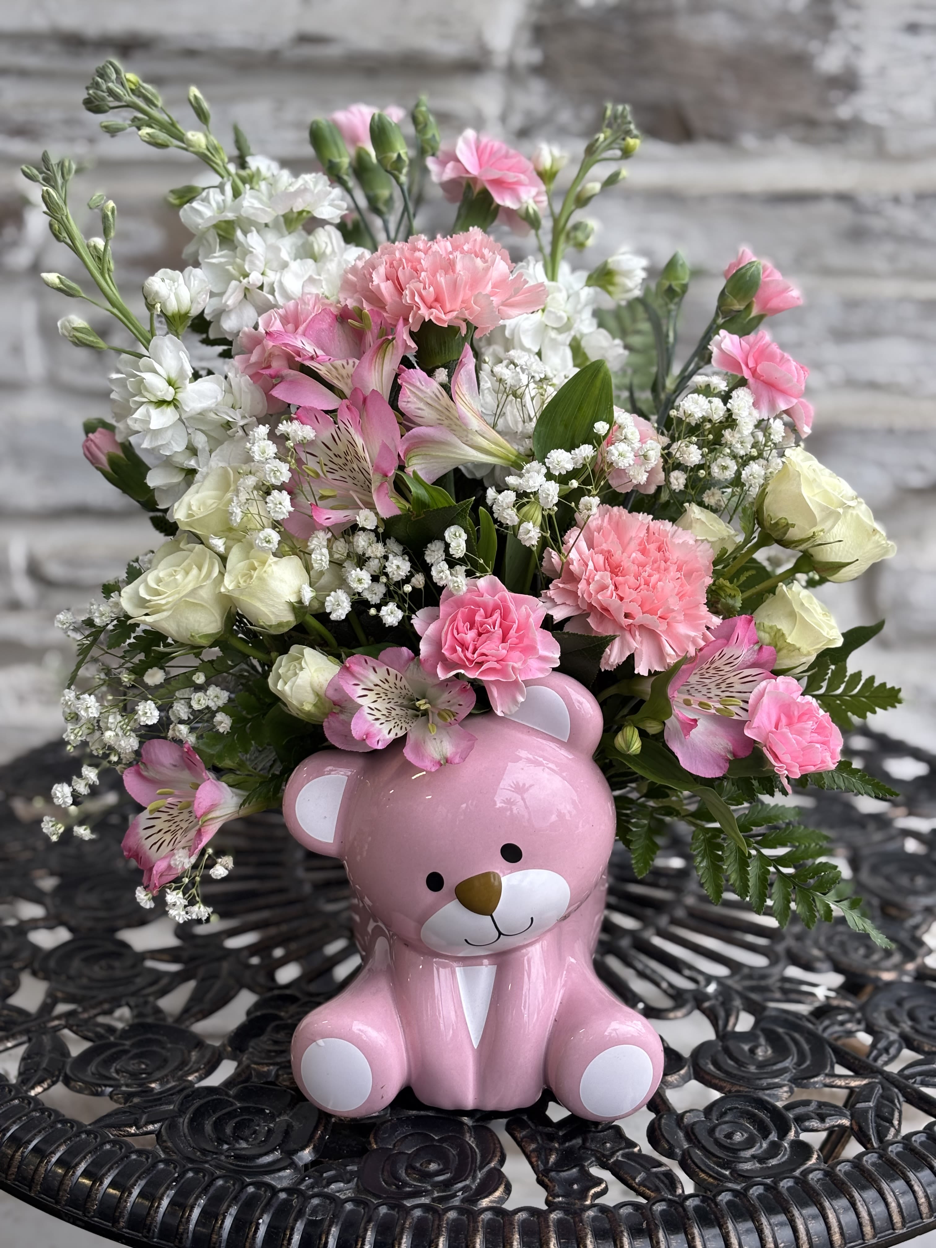Pink and white flower arrangement in a pink teddy bear container