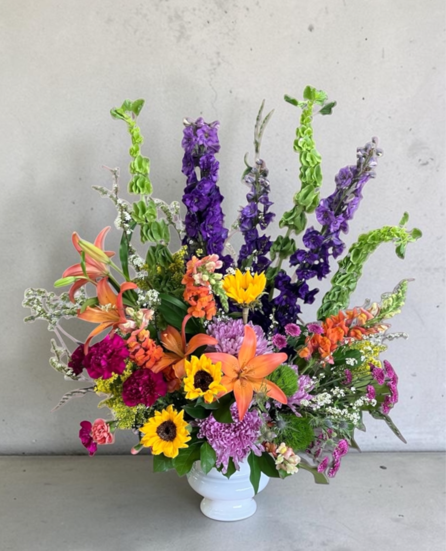 Colorful mixed flower arrangement in a white vase with tall purple spikes