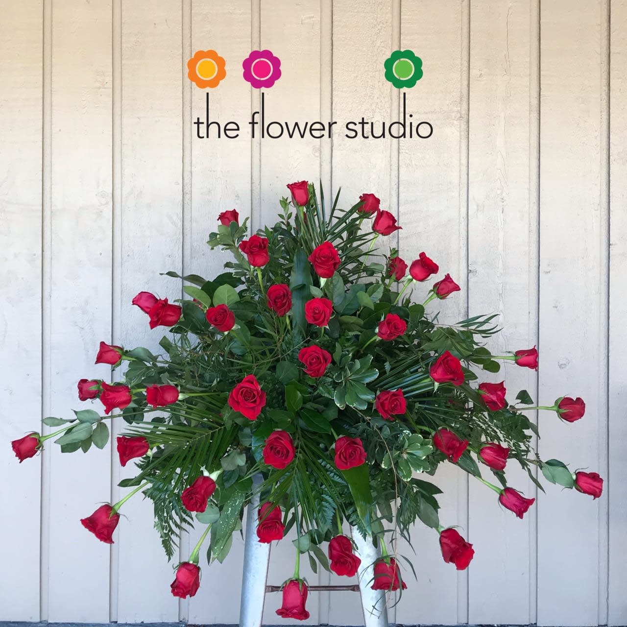 Large arrangement of red roses with greenery on a stand