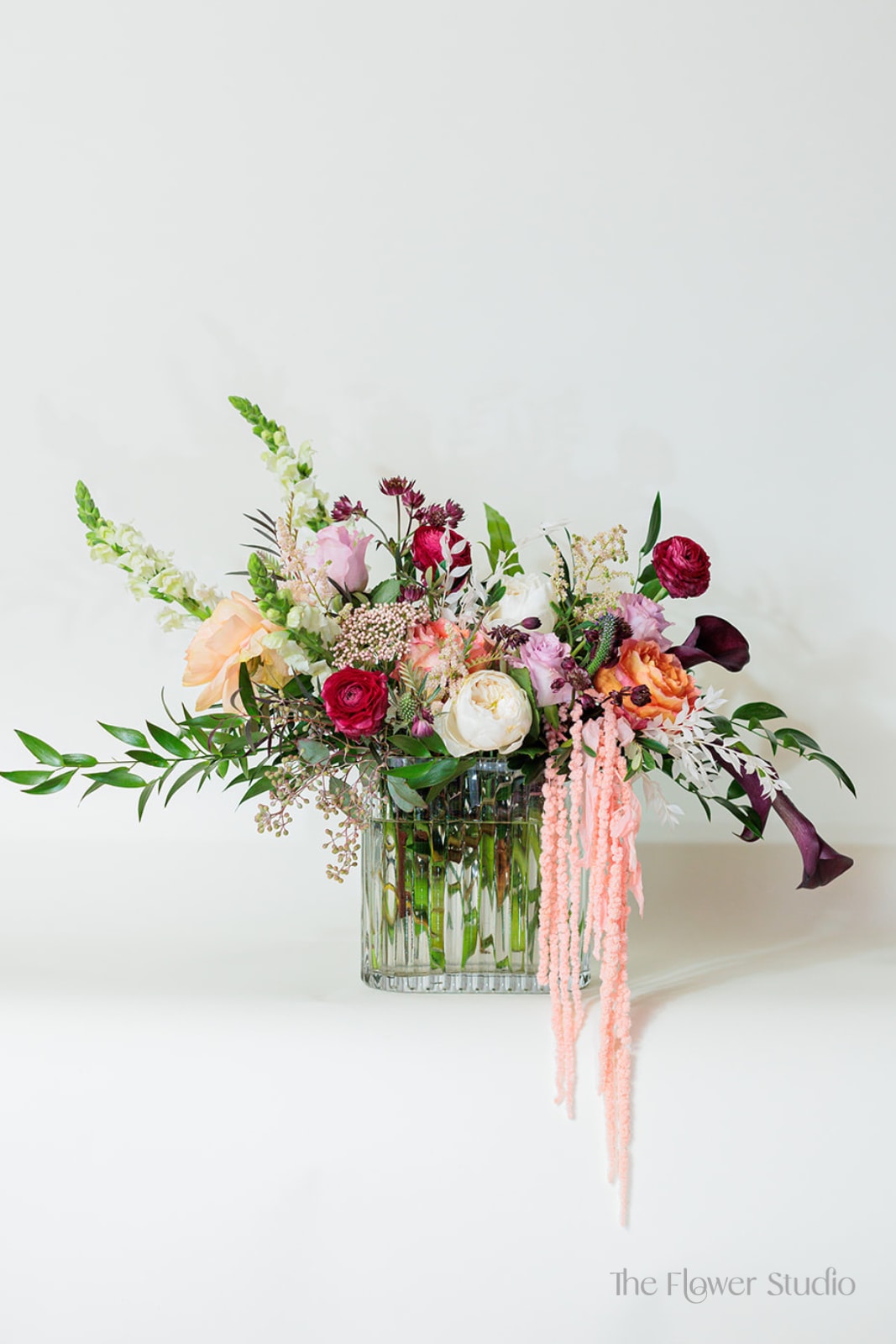 Mixed floral arrangement in a clear glass vase with pink, white, and burgundy blooms