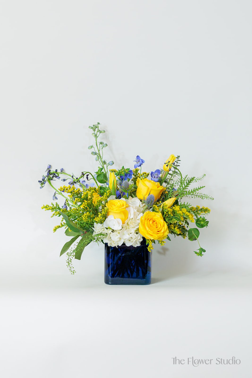 Yellow and blue floral arrangement in a dark blue vase