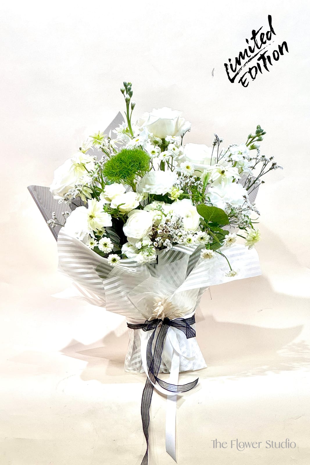 White bouquet with roses and small daisies wrapped in striped paper