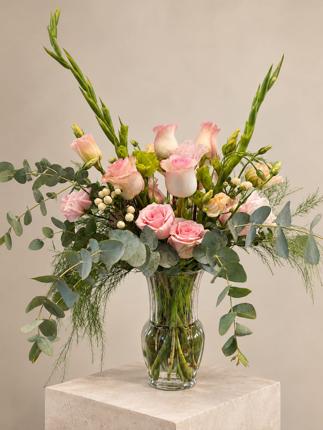 Pink roses and pale blooms arranged in a clear glass vase