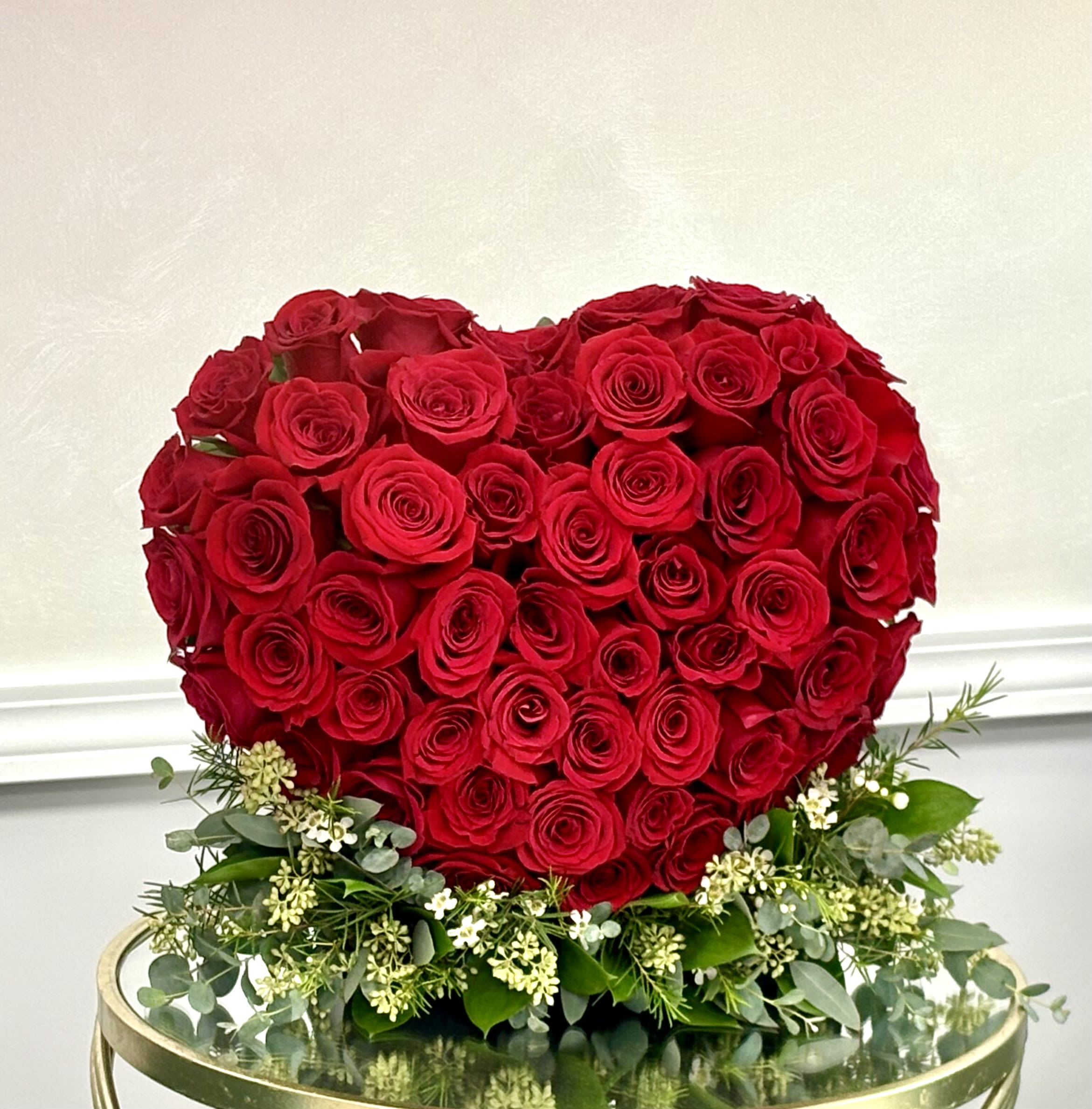 Heart-shaped arrangement of red roses with white filler flowers