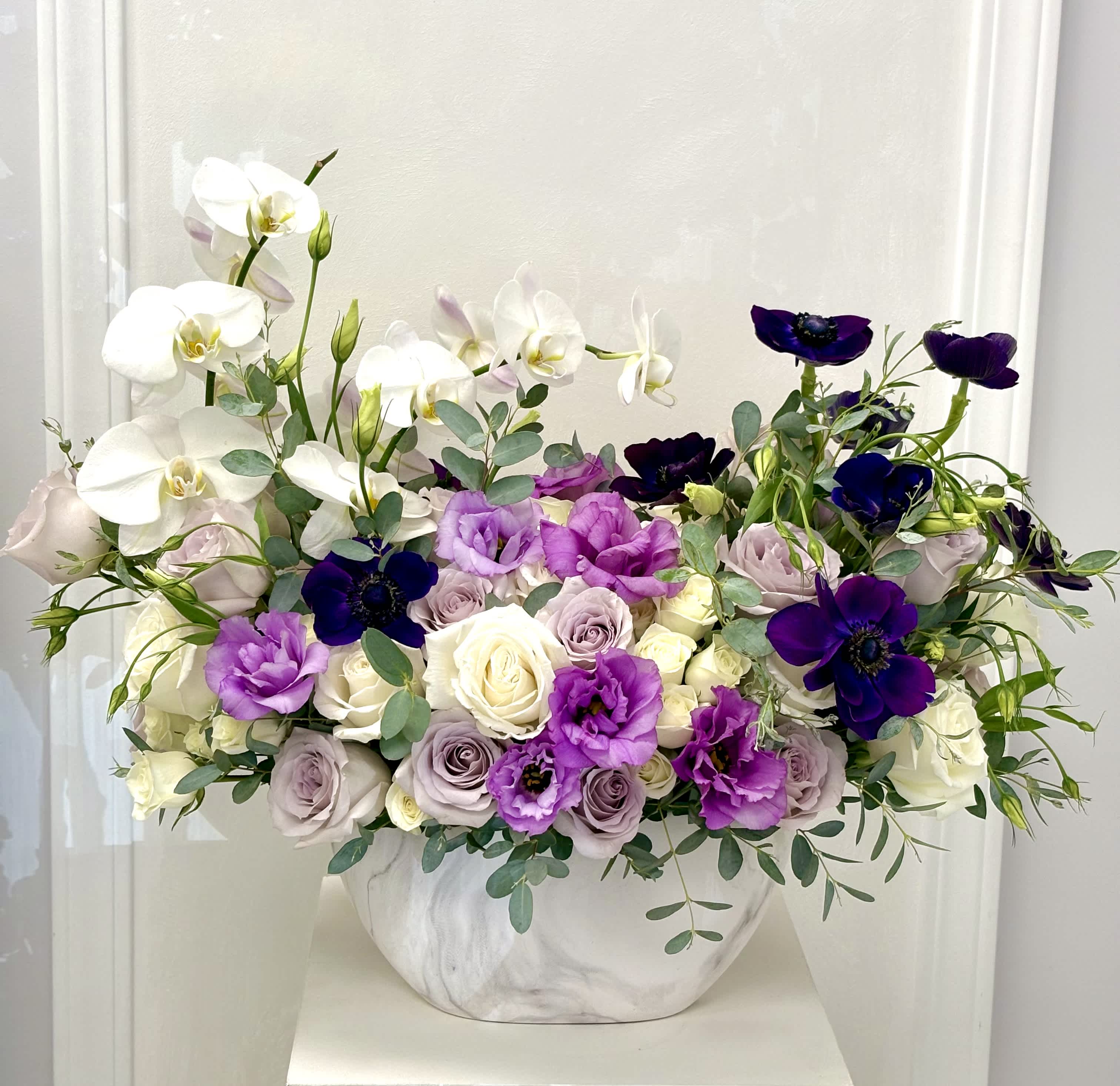 White orchids and purple flowers in a white vase