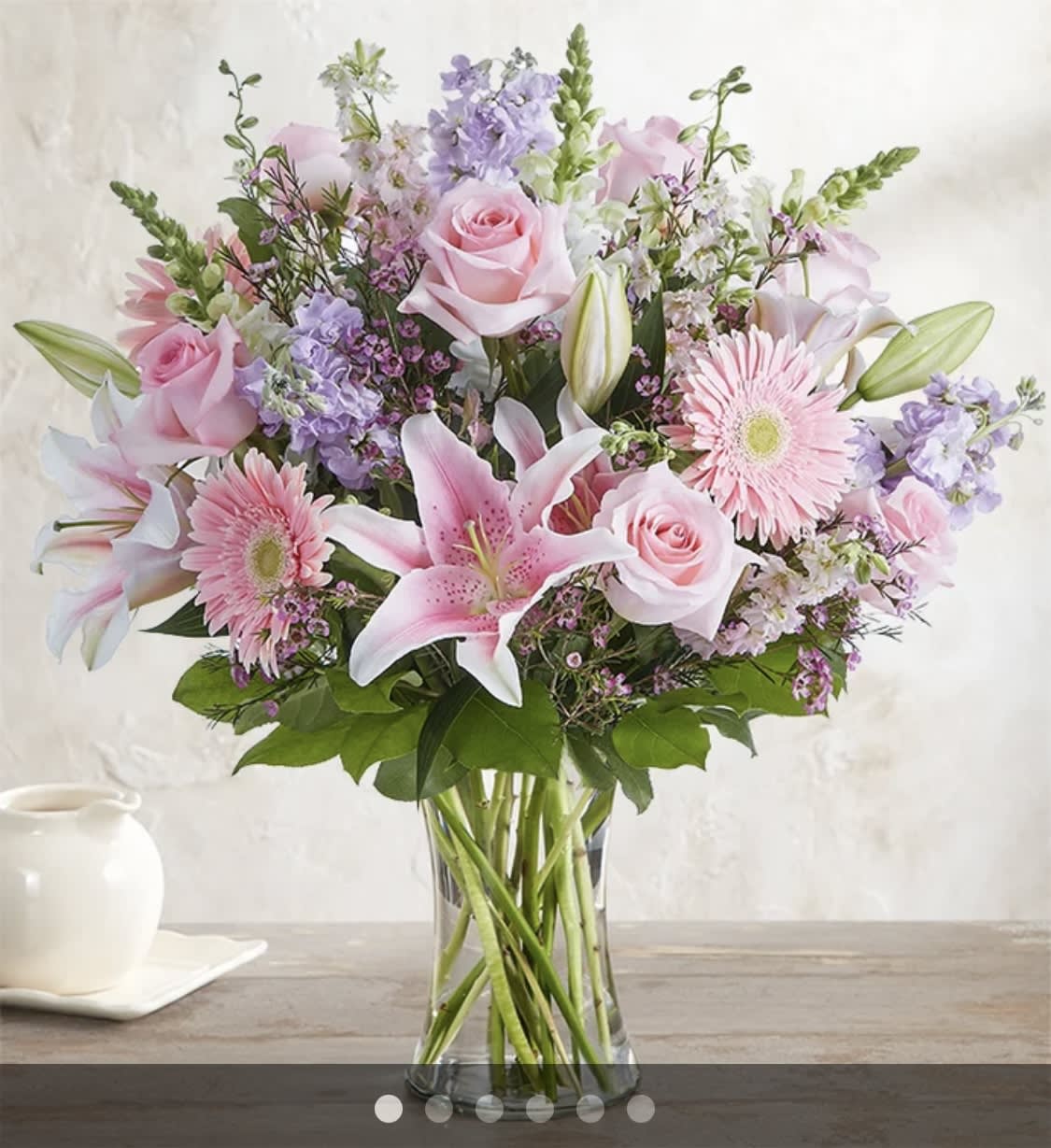 Pink roses, lilies, and gerbera daisies in a clear glass vase