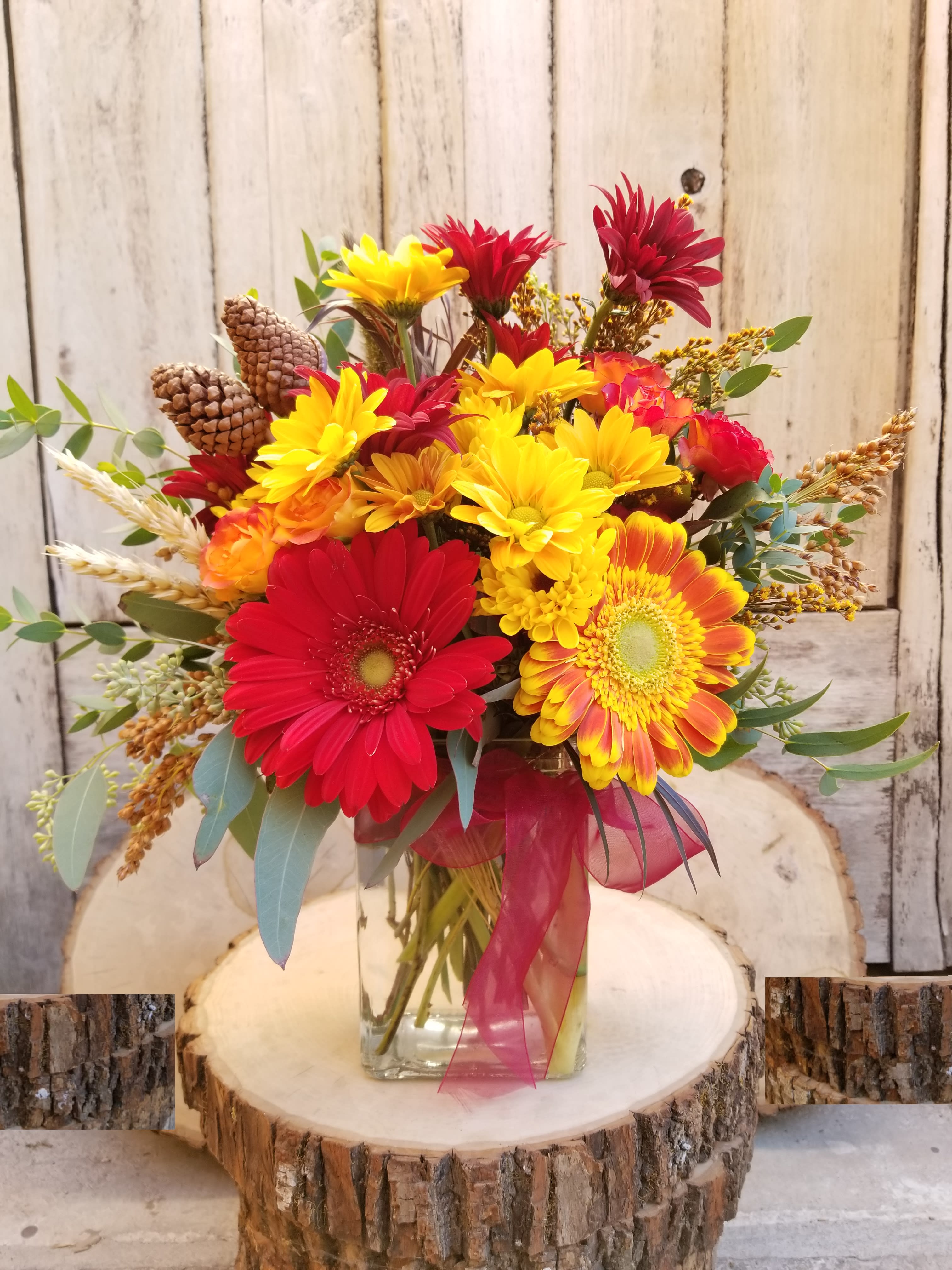 Bright Fall Arrangement - Bright colors of fall collaborate in a mini Autumnal garden Cylinder vase. Upgrades go in a larger vase with more flowers and full size roses in the same colors.   Shown is standard arrangement and measures approx 11" tall