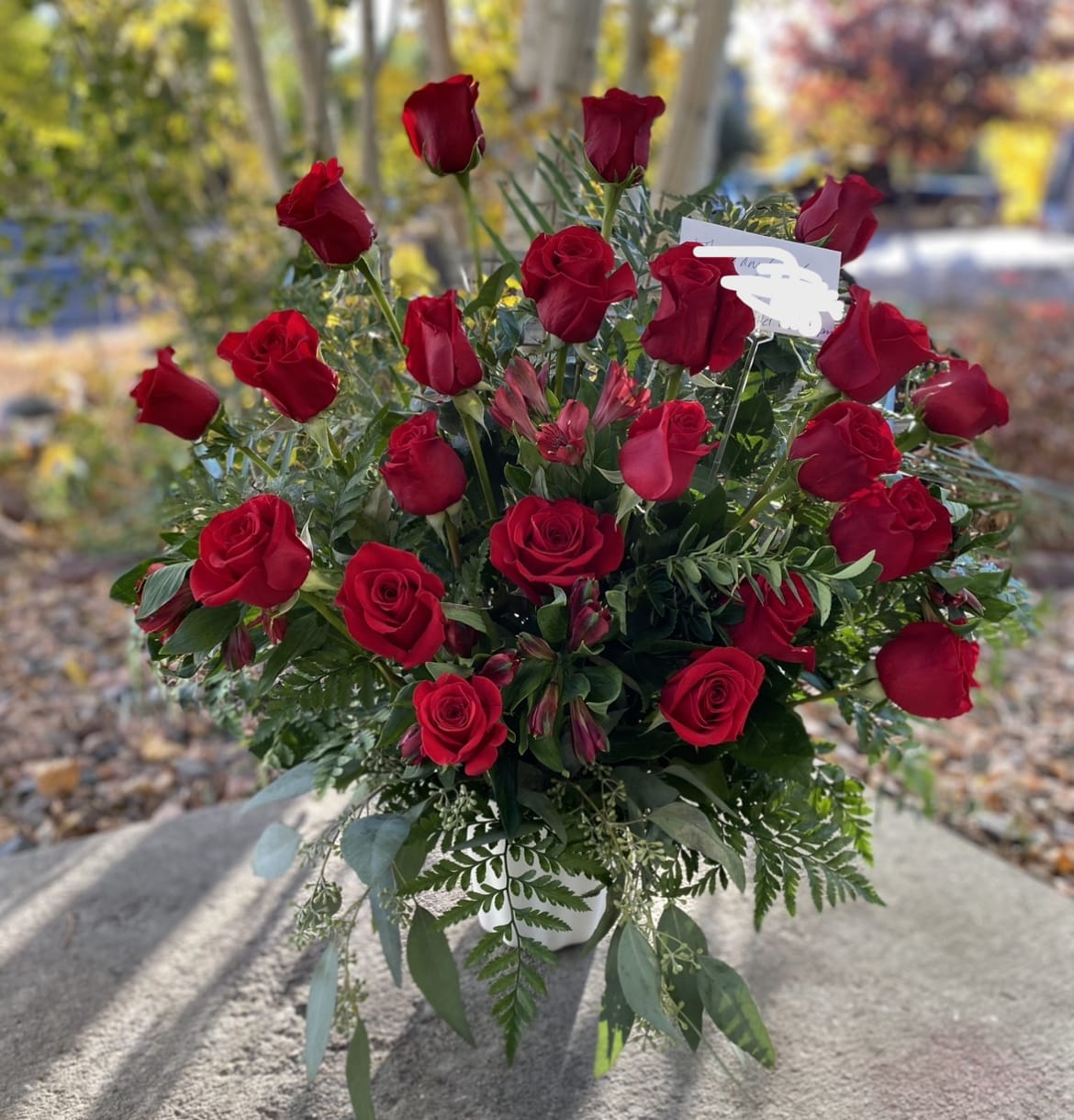 Bouquet of red roses with greenery in a white vase
