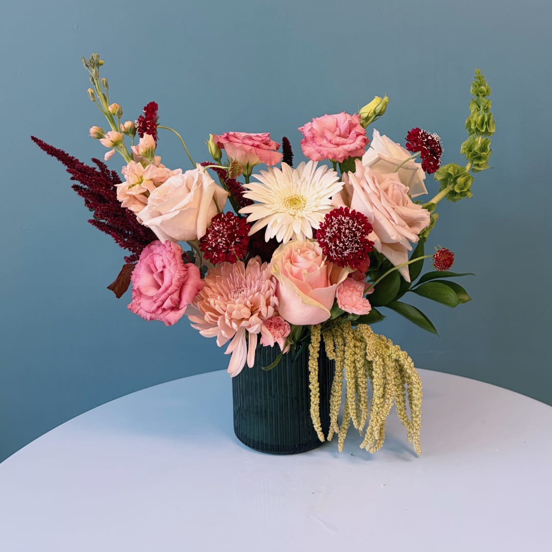 Mixed pink and white floral arrangement in a dark ribbed vase