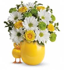 Yellow and white flower arrangement in a yellow vase with a chick figurine