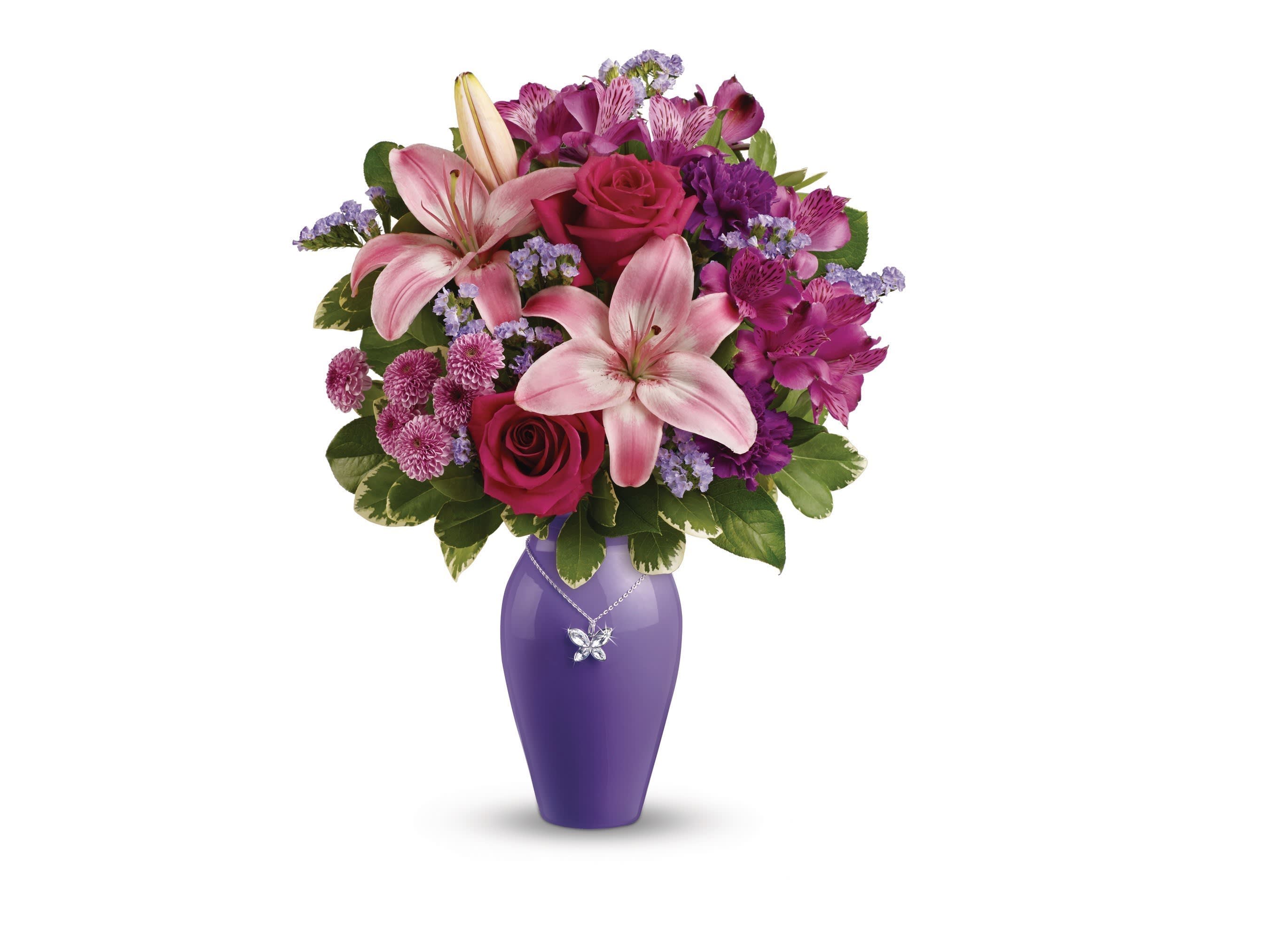 Pink lilies and roses in a purple vase with a butterfly necklace