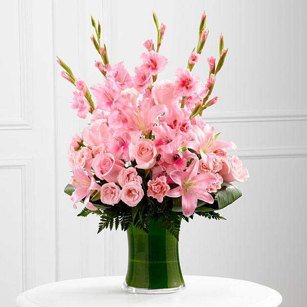 Pink lilies, roses, and carnations in a green glass vase