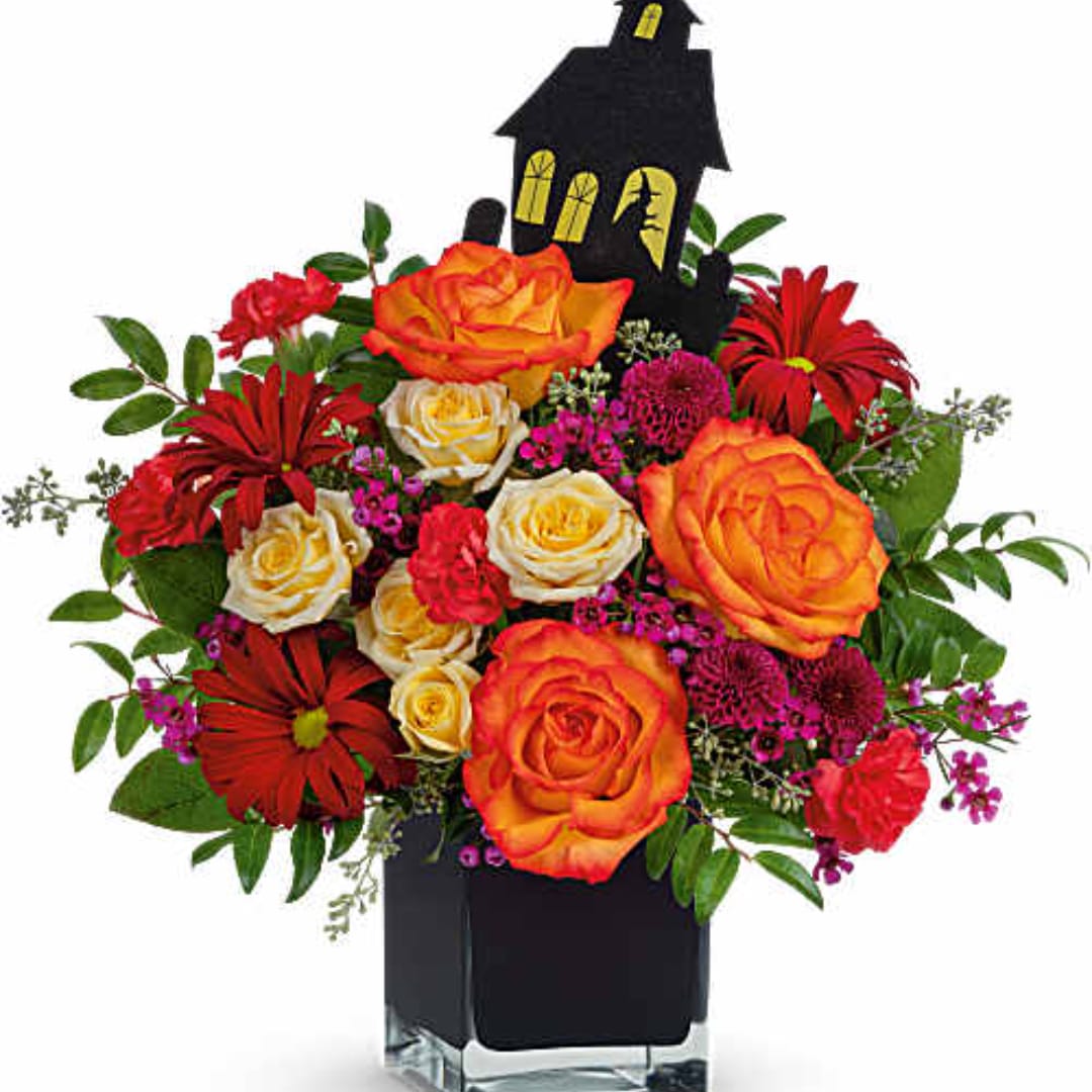 Bouquet of orange roses and red daisies in a black vase with a Halloween house pick