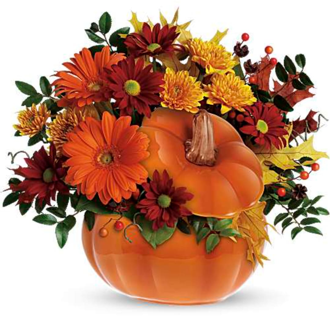 Autumn floral arrangement in a pumpkin-shaped container with orange and burgundy blooms