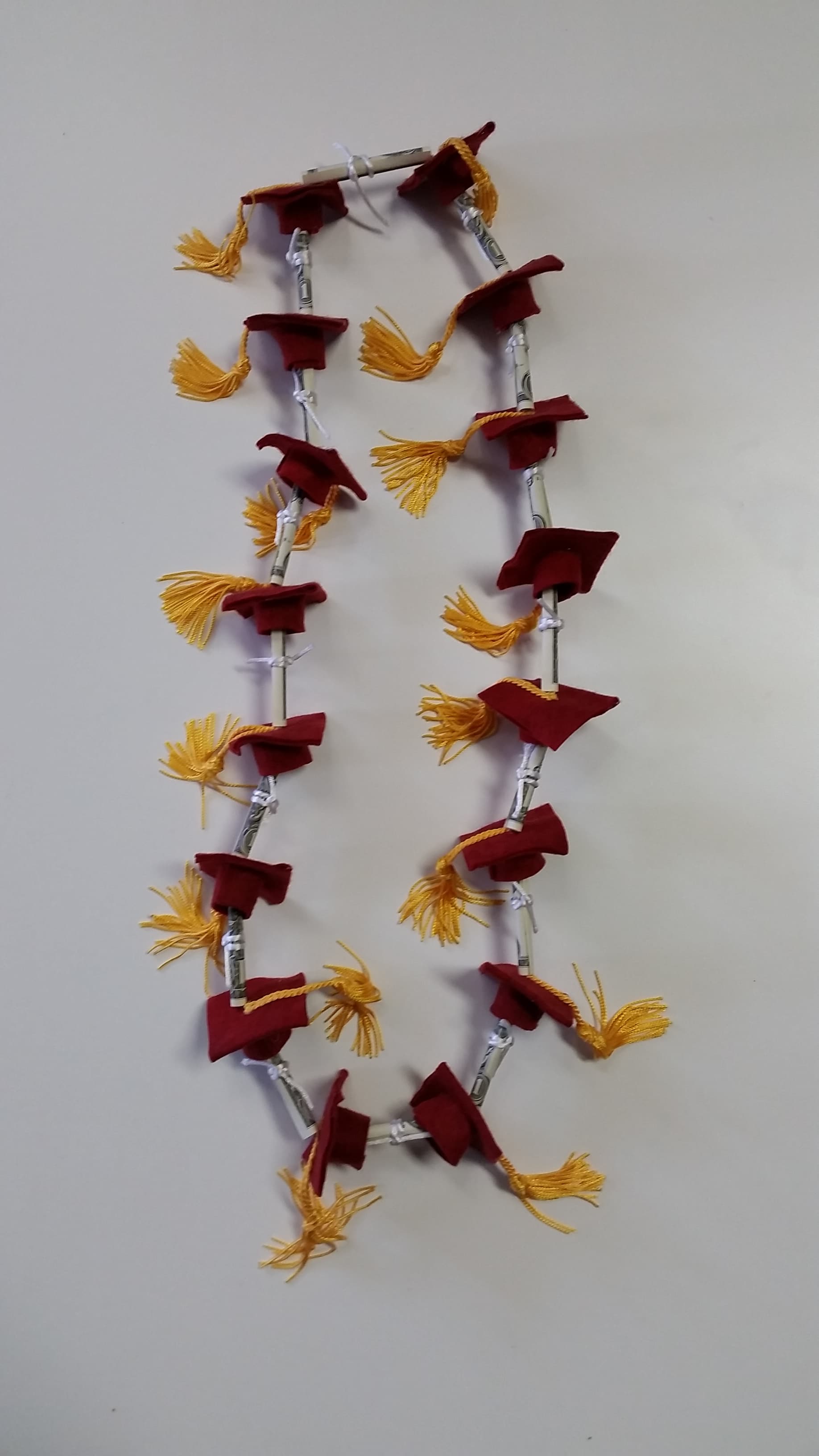 Maroon graduation stole with gold tassels hanging on a wall