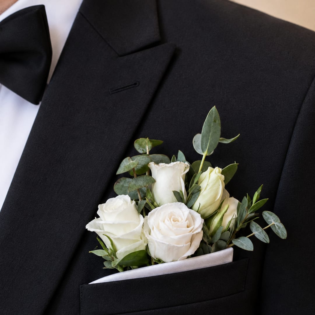 White rose boutonniere in a black suit pocket