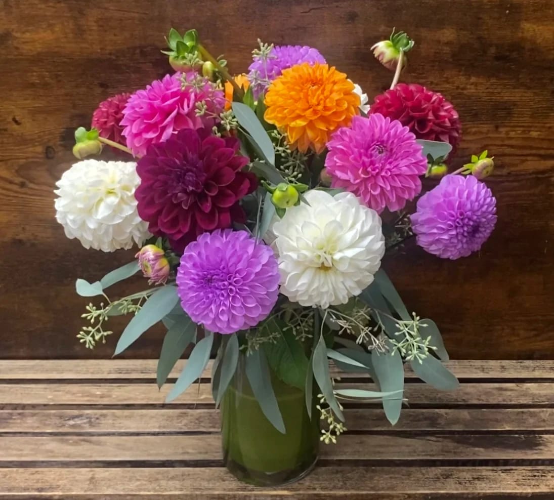 Bouquet of colorful dahlias in a green glass vase