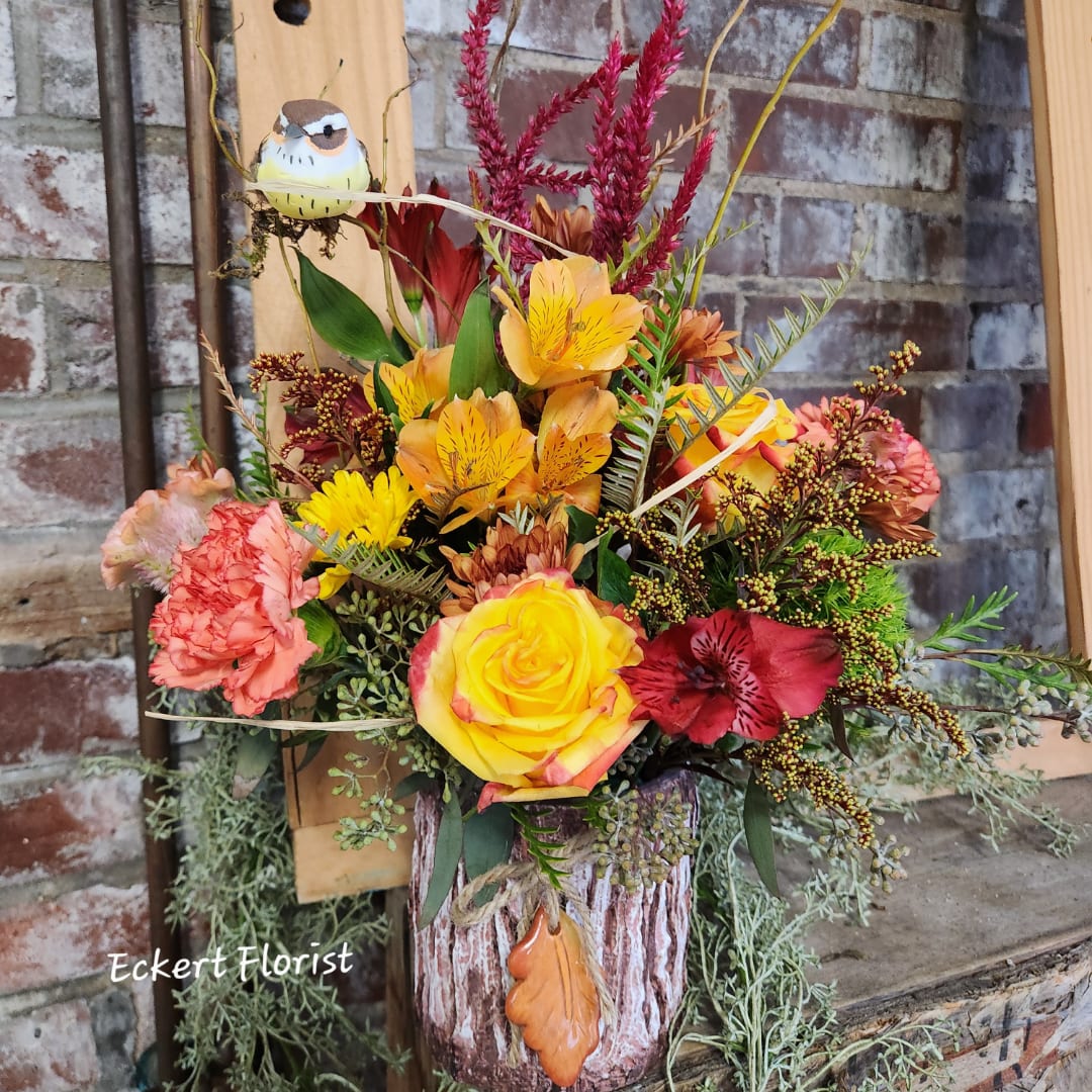 Autumn floral arrangement in a rustic vase with a small bird ornament.