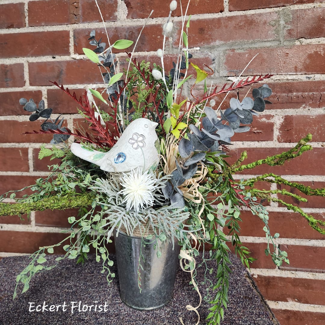 Mixed floral arrangement in a metal vase with a decorative white bird.