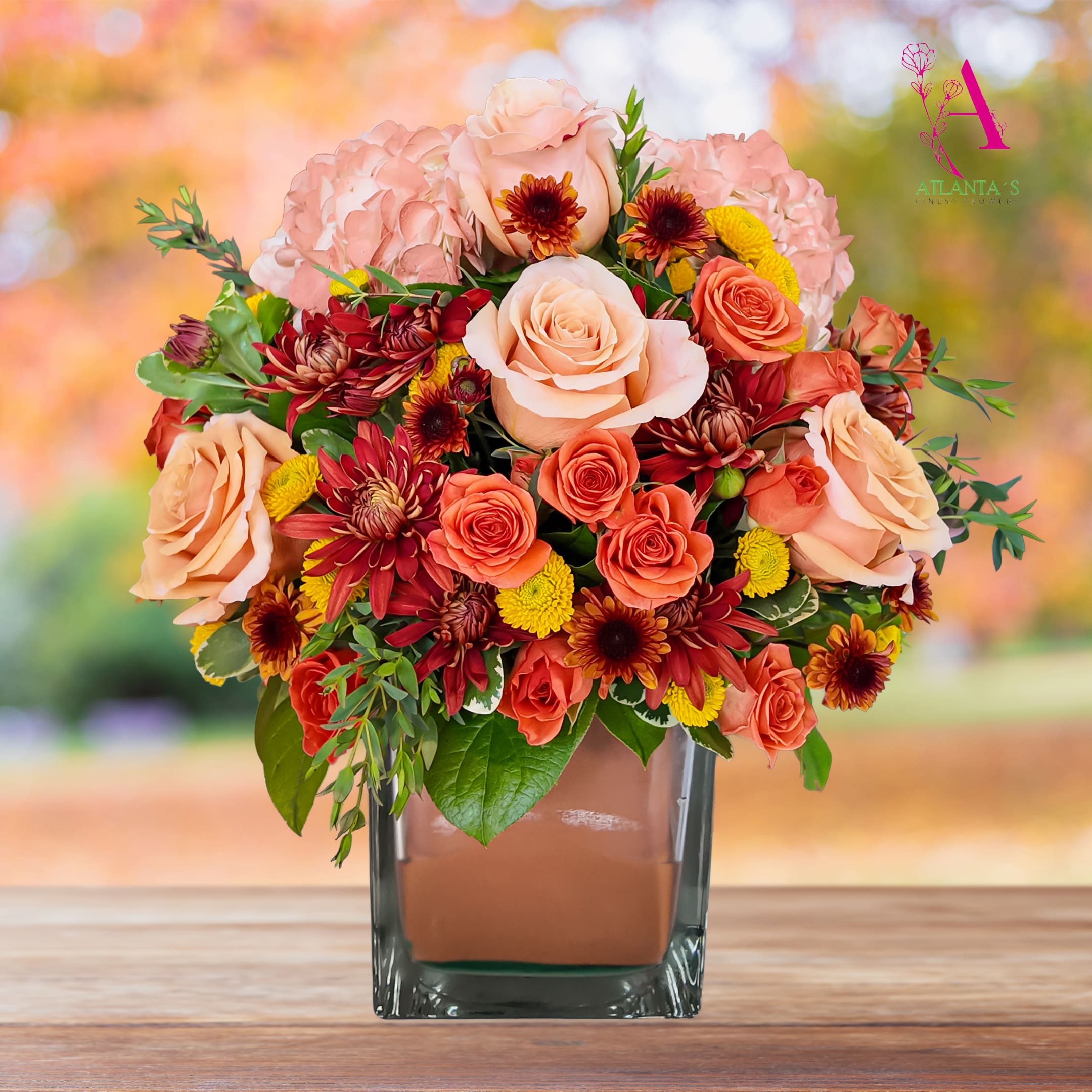 Peach and coral roses with pink hydrangeas in a square glass vase