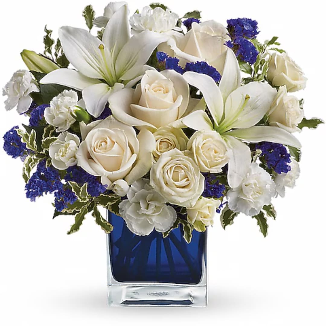 White roses and lilies arranged in a blue glass vase