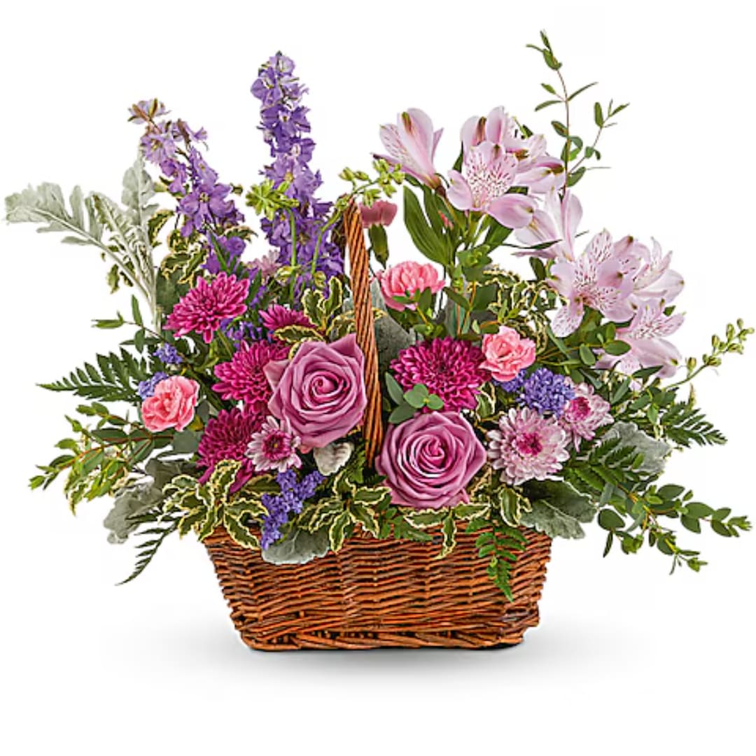 Mixed pink and purple flowers arranged in a wicker basket
