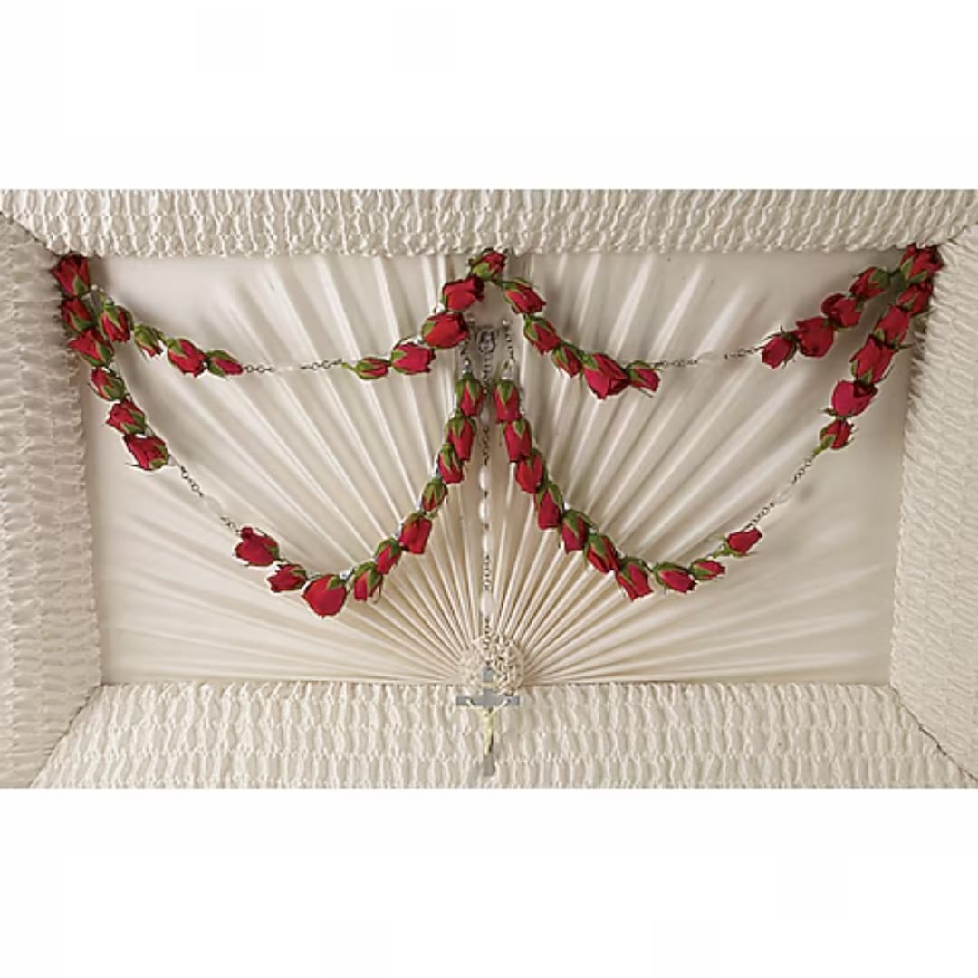 White coffin spray with red rose garlands and a cross pendant