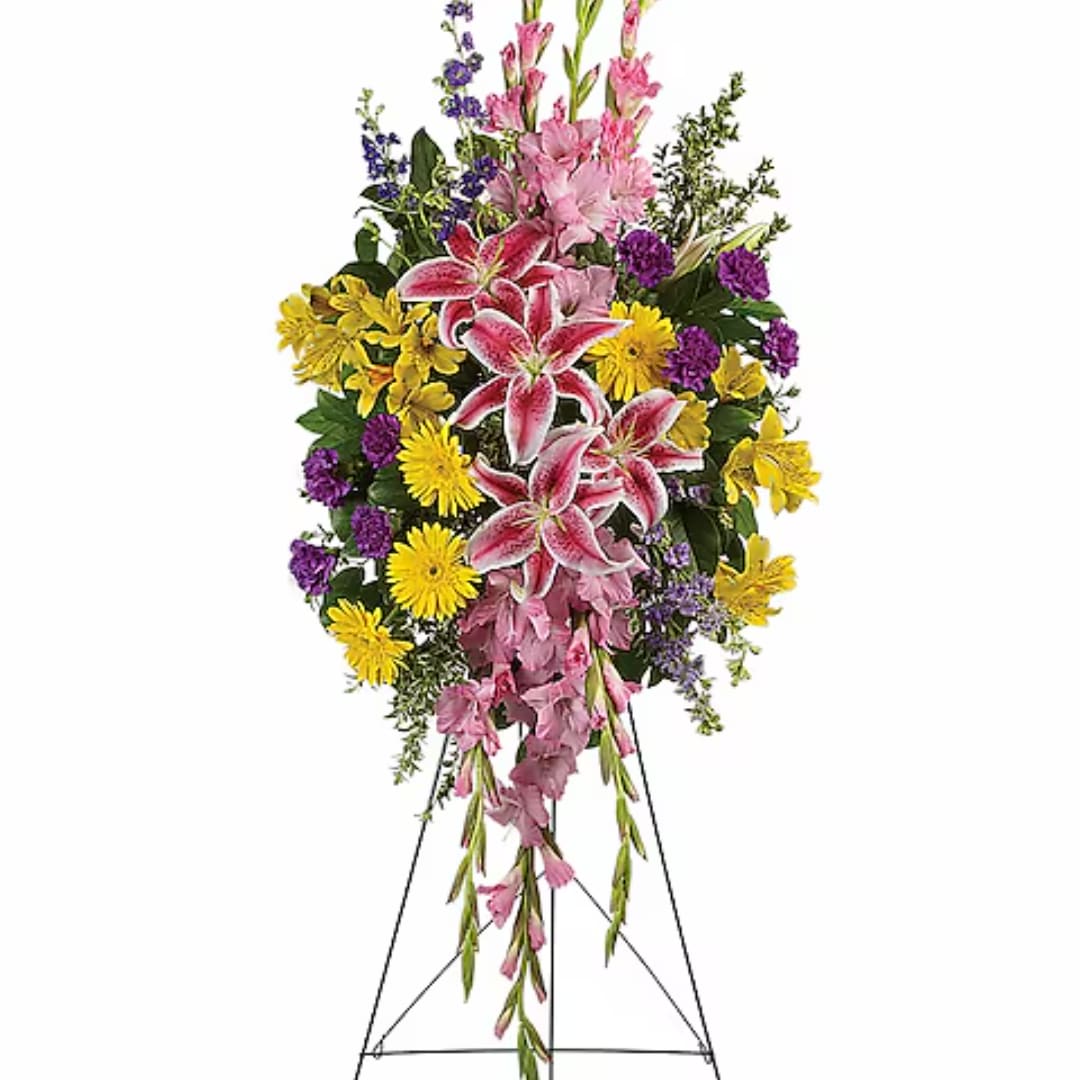 Standing floral spray with pink lilies, yellow daisies, and purple accents