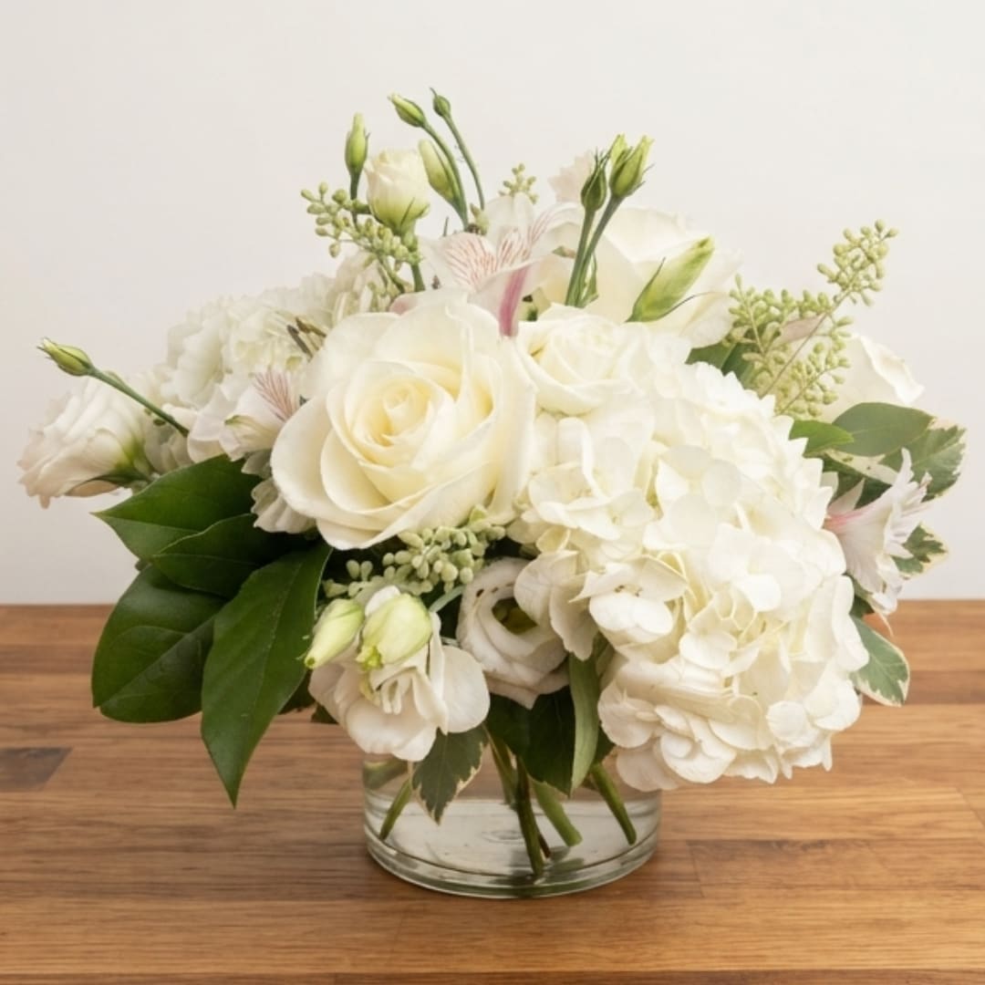White roses and hydrangeas arranged in a clear glass vase