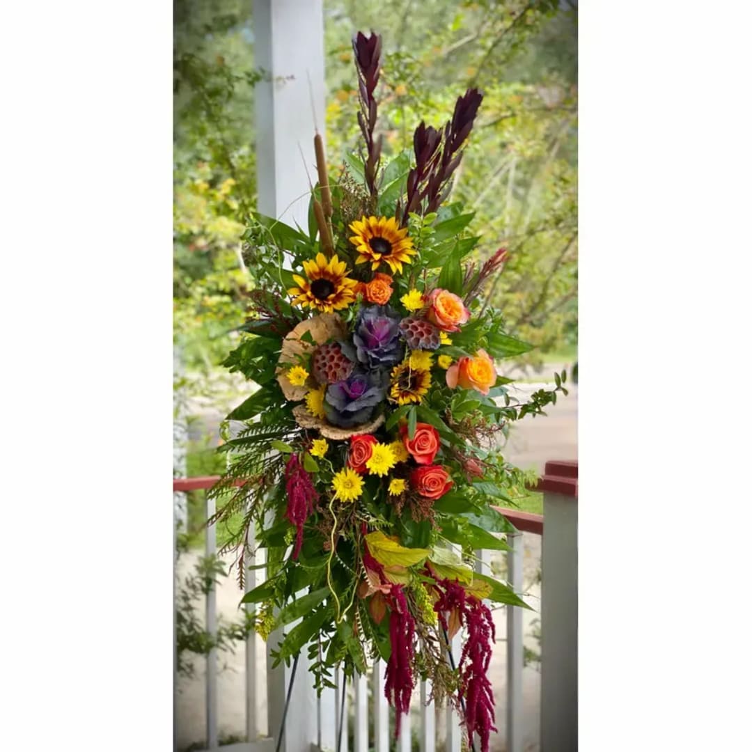 Tall mixed floral arrangement with sunflowers, roses, and purple accents