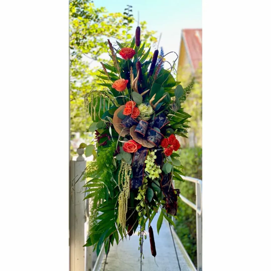 Tall tropical floral arrangement with red roses and dark foliage