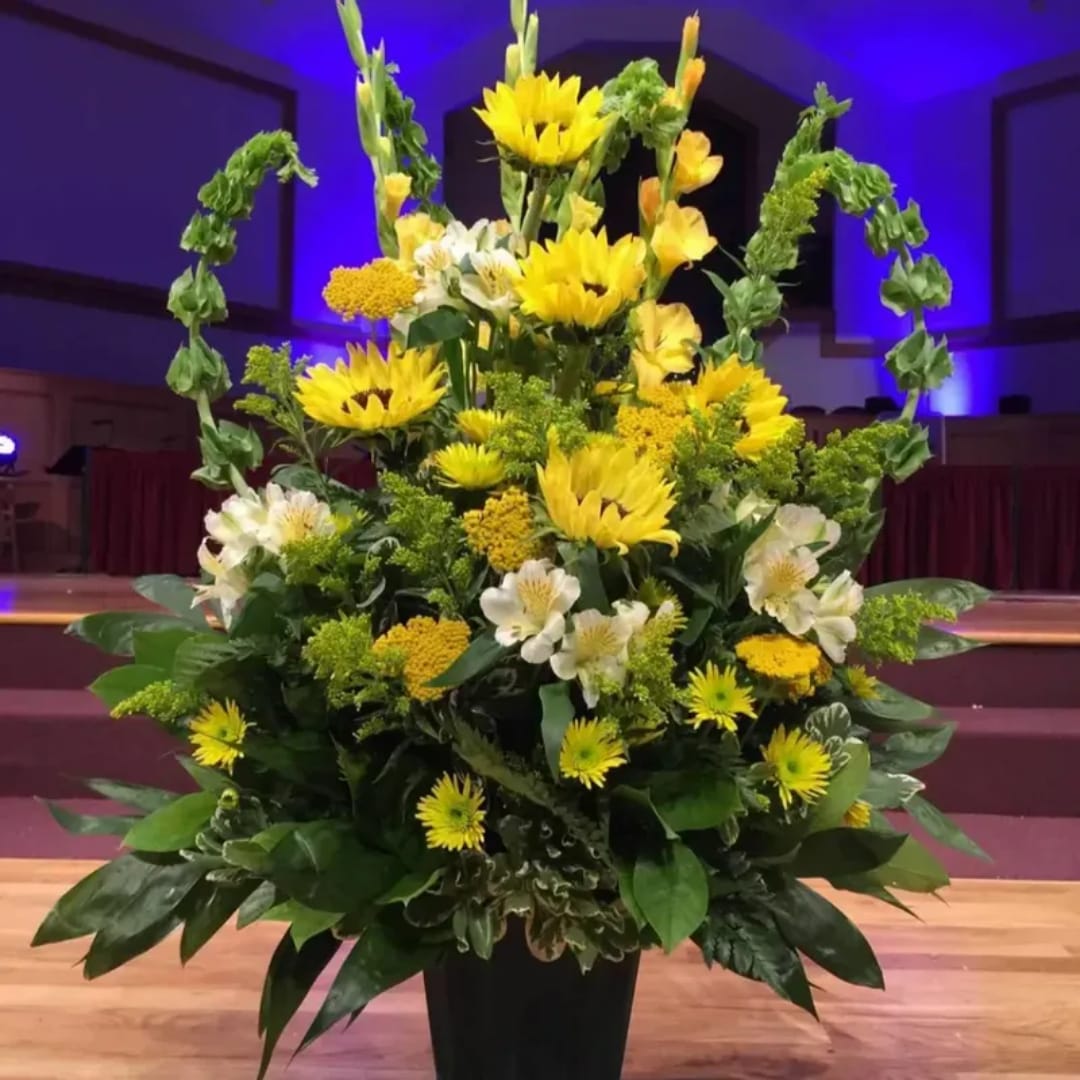 Tall yellow and white floral arrangement in a black vase